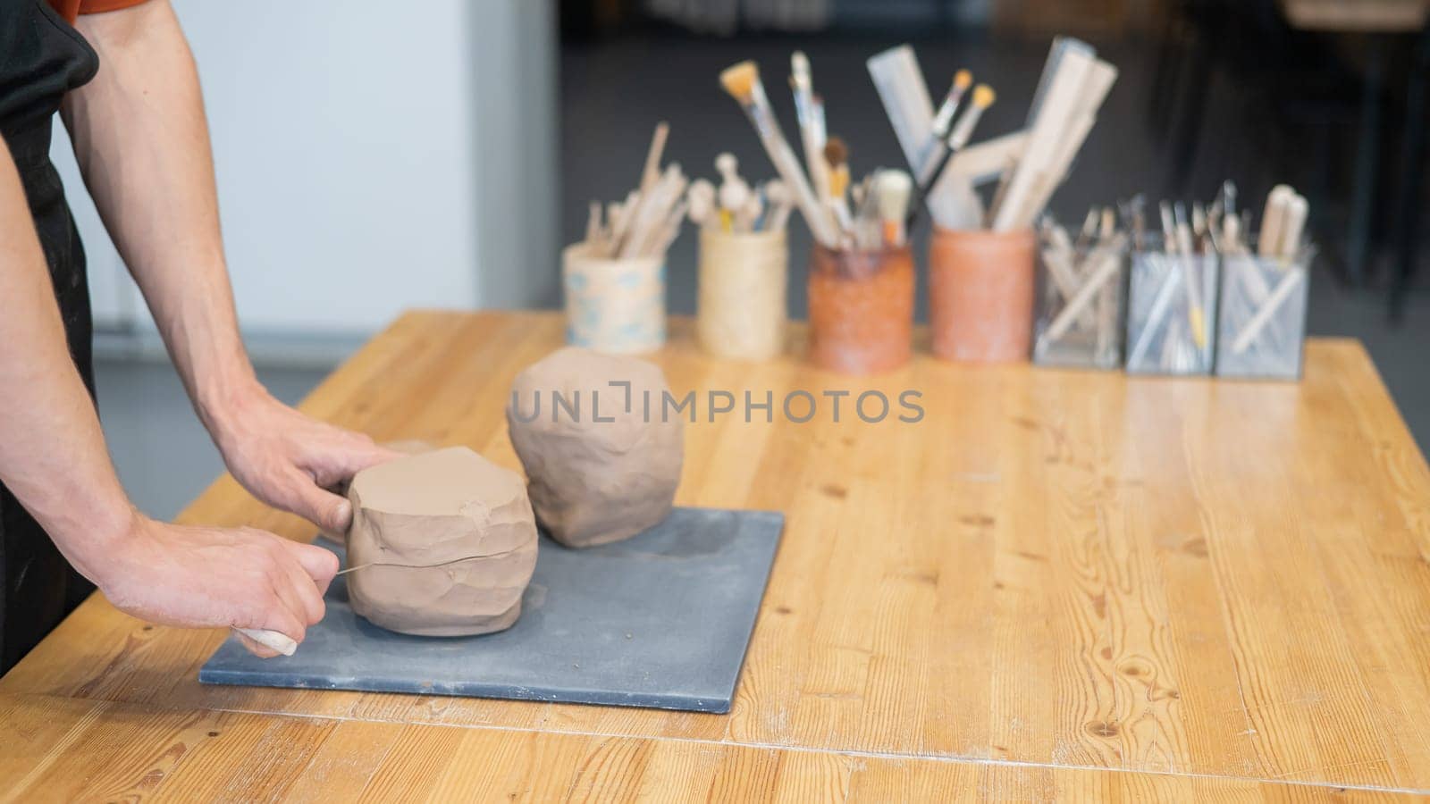 A potter cuts a piece of clay into pieces before using it in the workshop. by mrwed54