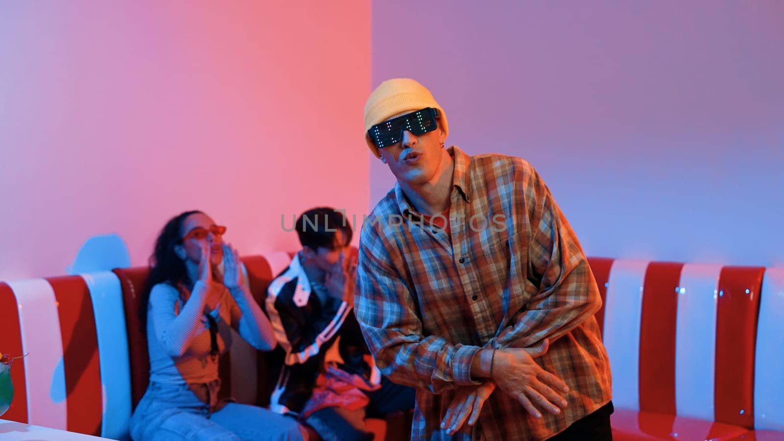 Caucasian break dancer perform movement while diverse friend sitting and dancing together. Happy hipster moving hand while multicultural group waving hand to support and encourage friend. Regalement.