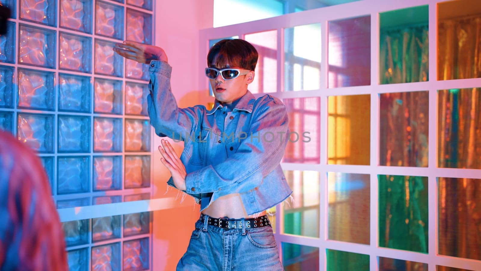 Professional happy hipster moving arm while dancing at center surrounded by diverse friend cheering him. Attractive asian break performing energetic footstep with neon light at nightclub. Regalement.