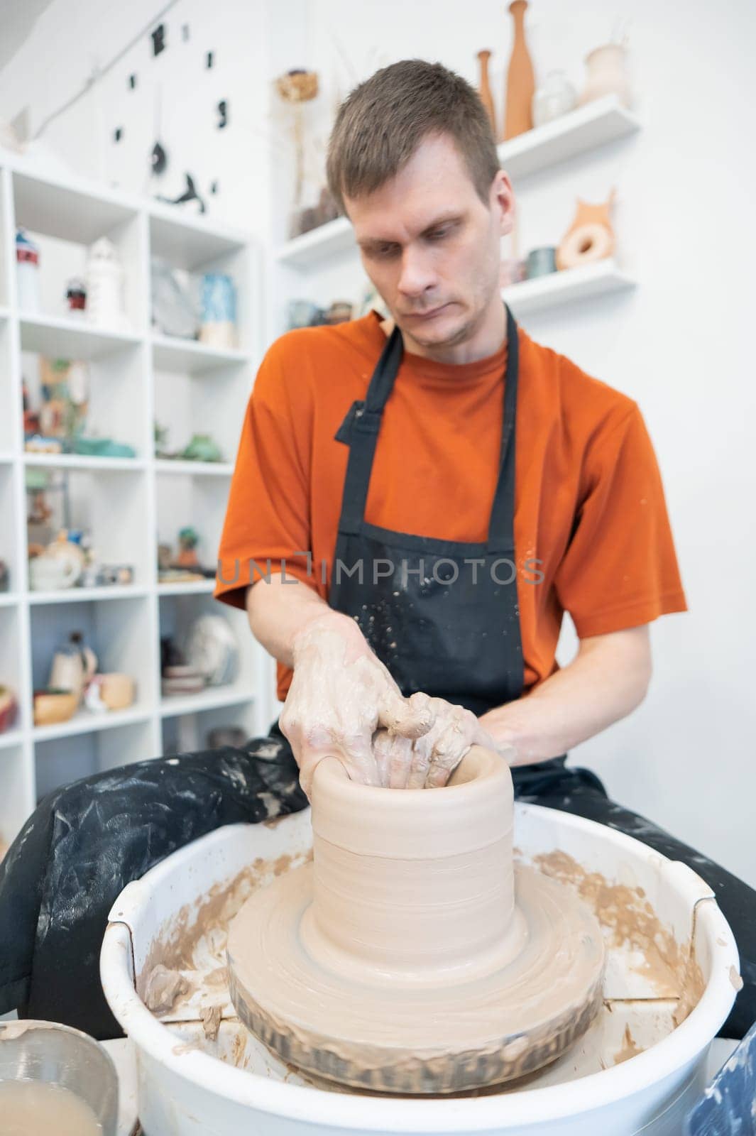 A potter working on a potter's wheel. Vertical photo. by mrwed54