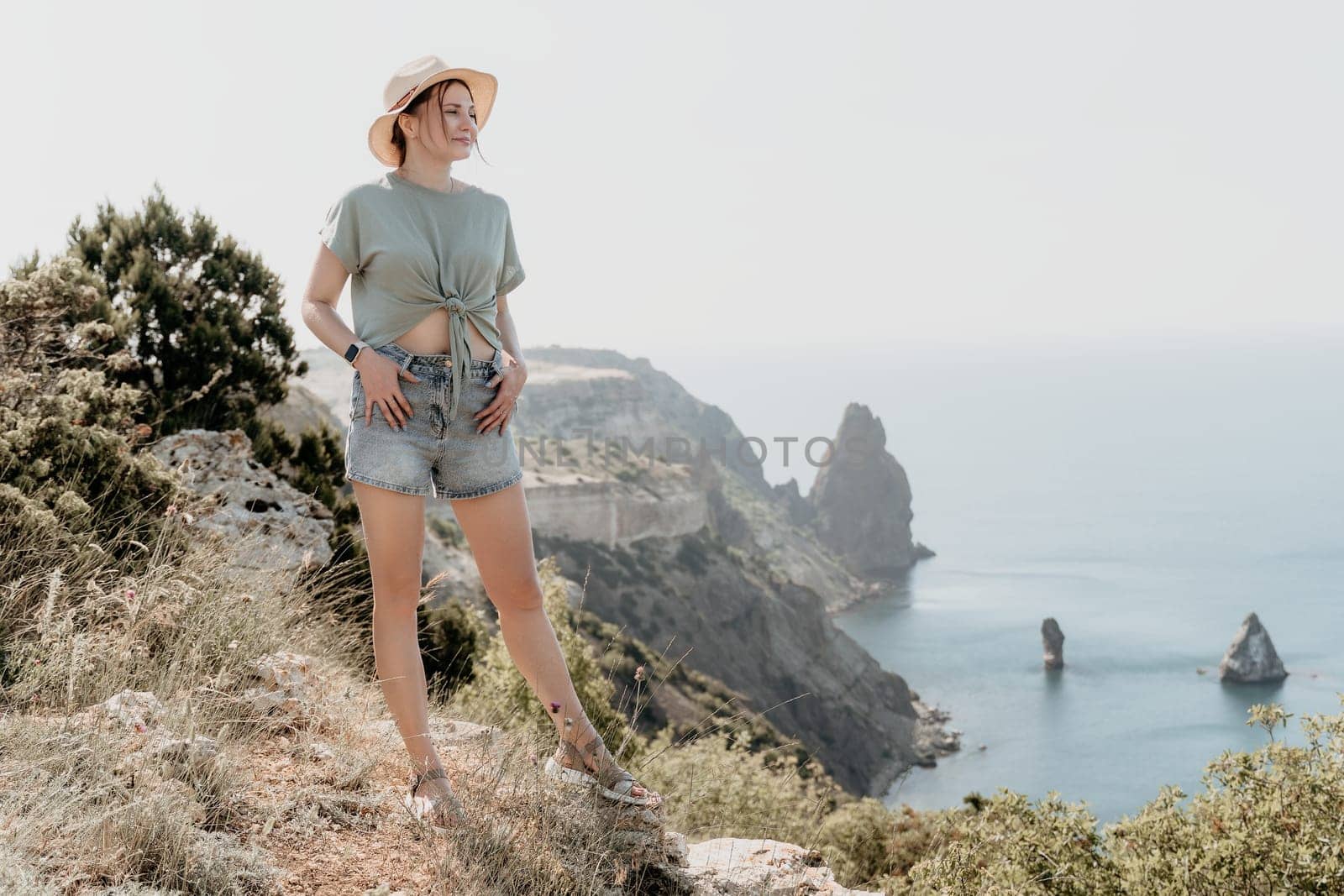 Woman travel sea. Happy tourist in hat enjoy taking picture outdoors for memories. Woman traveler posing on the beach at sea surrounded by volcanic mountains, sharing travel adventure journey by panophotograph