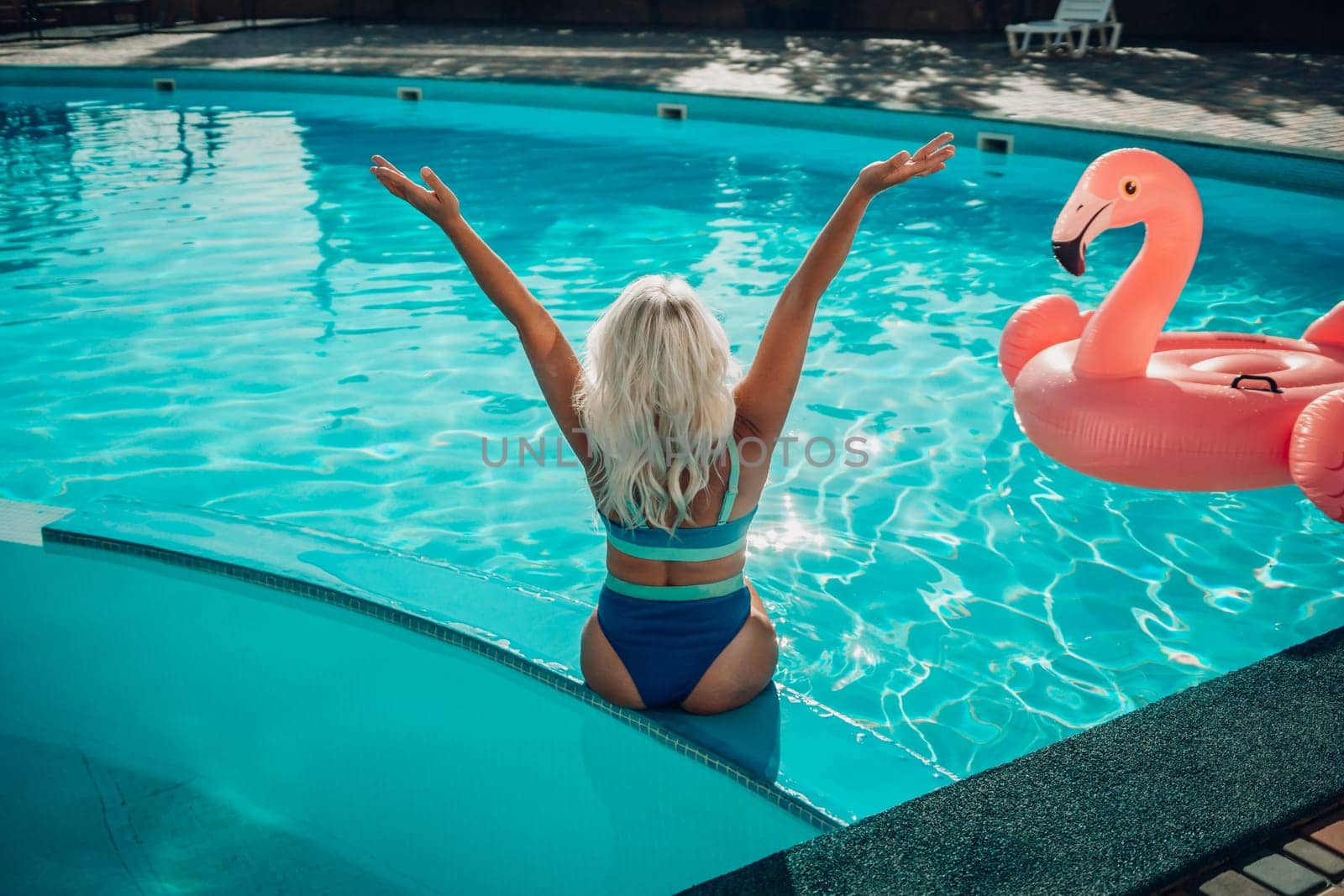 Happy woman in bikini sitting near swimming pool, summer vacation