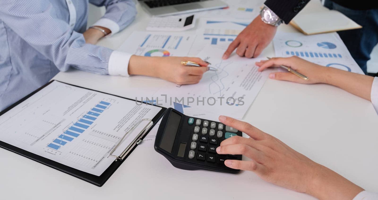 A group of accountants working together on financial calculations, analyzing data, and discussing reports in a professional office environment.