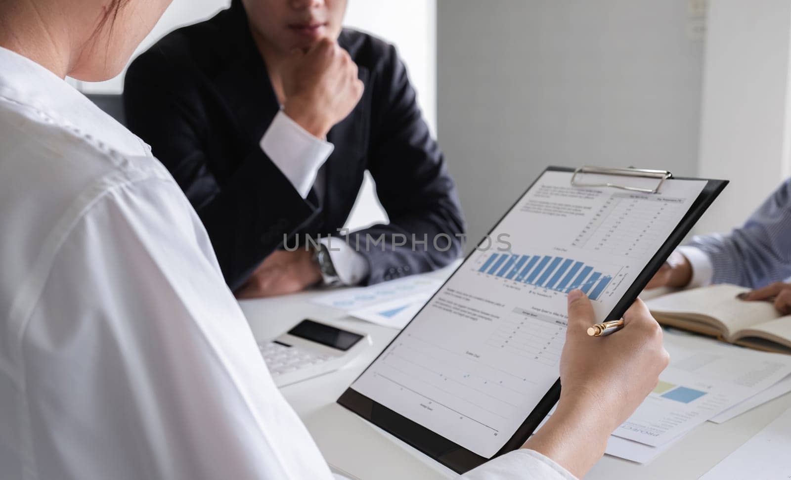 A group of professional accountants meeting to review and discuss financial calculations, charts, and data in a contemporary office environment.