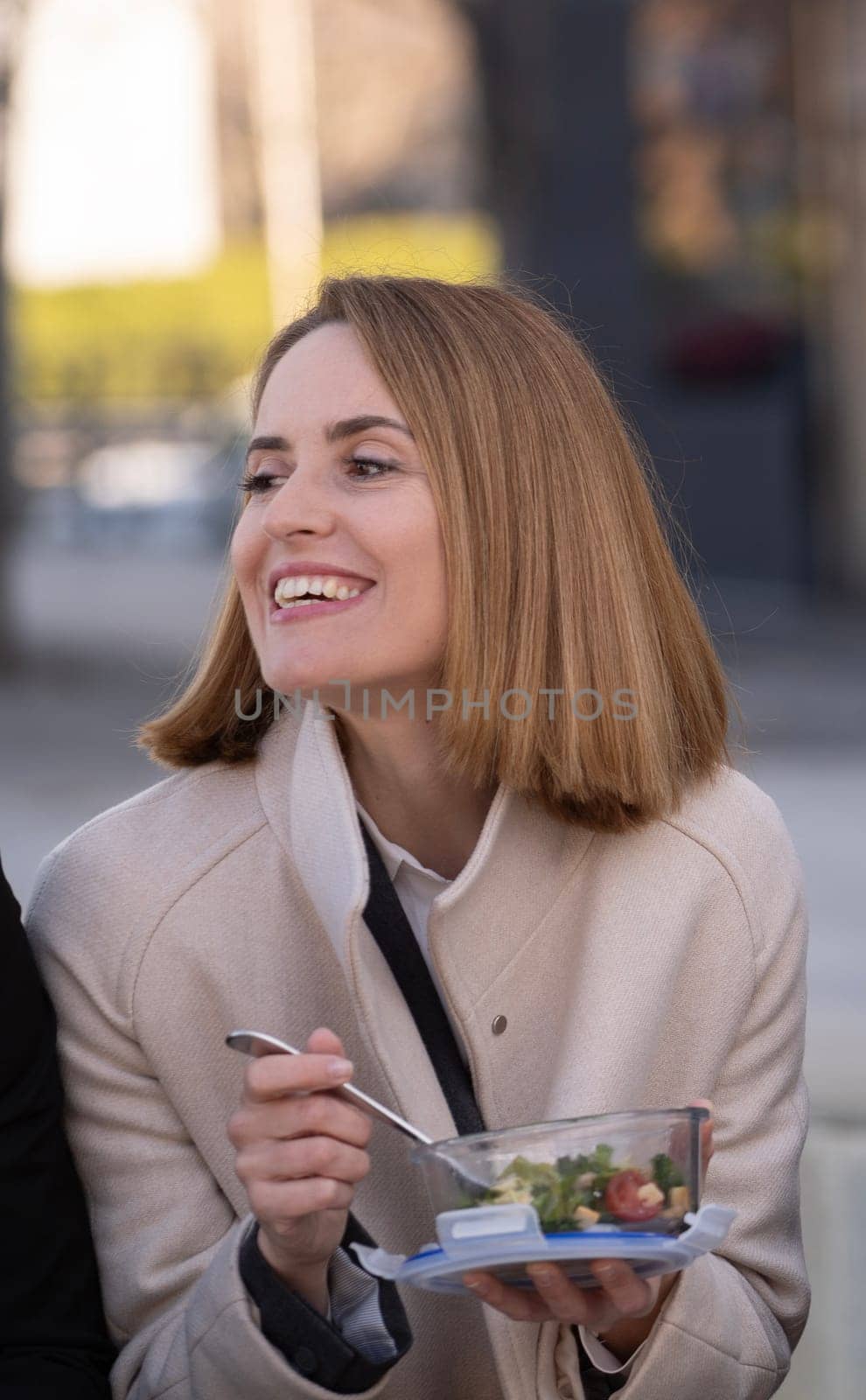 Portrait of a smiling business woman on a lunch break outdoors eating a healthy salad.