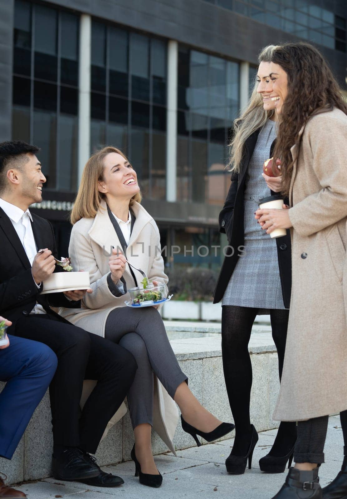 Multiethnic business people eating takeaway food during lunch break outdoor outside the office.