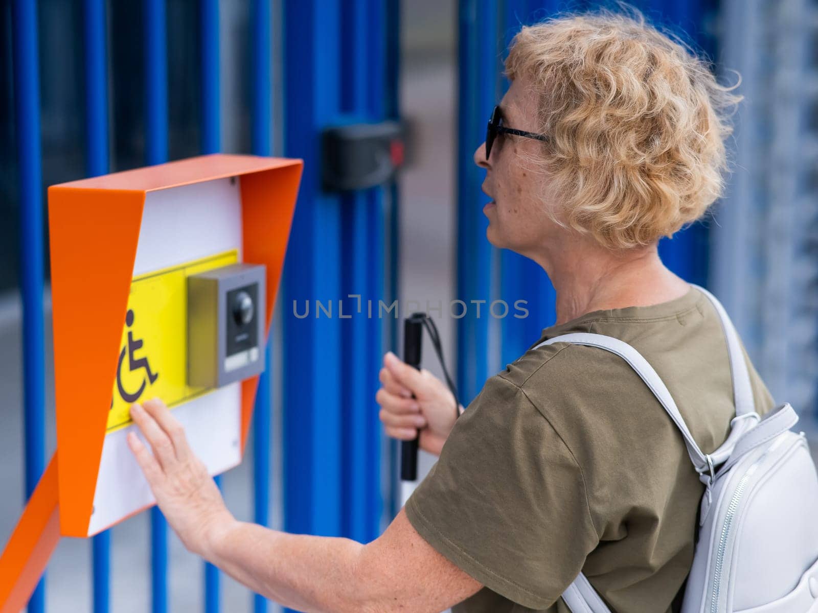 An elderly blind woman reading a text in braille. Button for calling help for people with disabilities