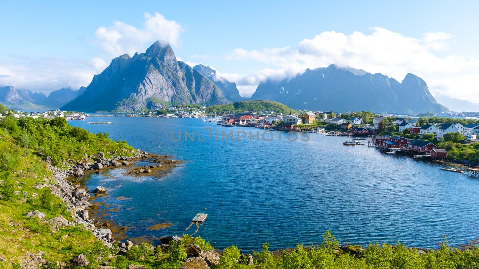 Norwegian fjord view with mountains, calm waters, and a quaint village. The scenery embodies the beauty and serenity of Norway. Reine, Lofoten, Norway