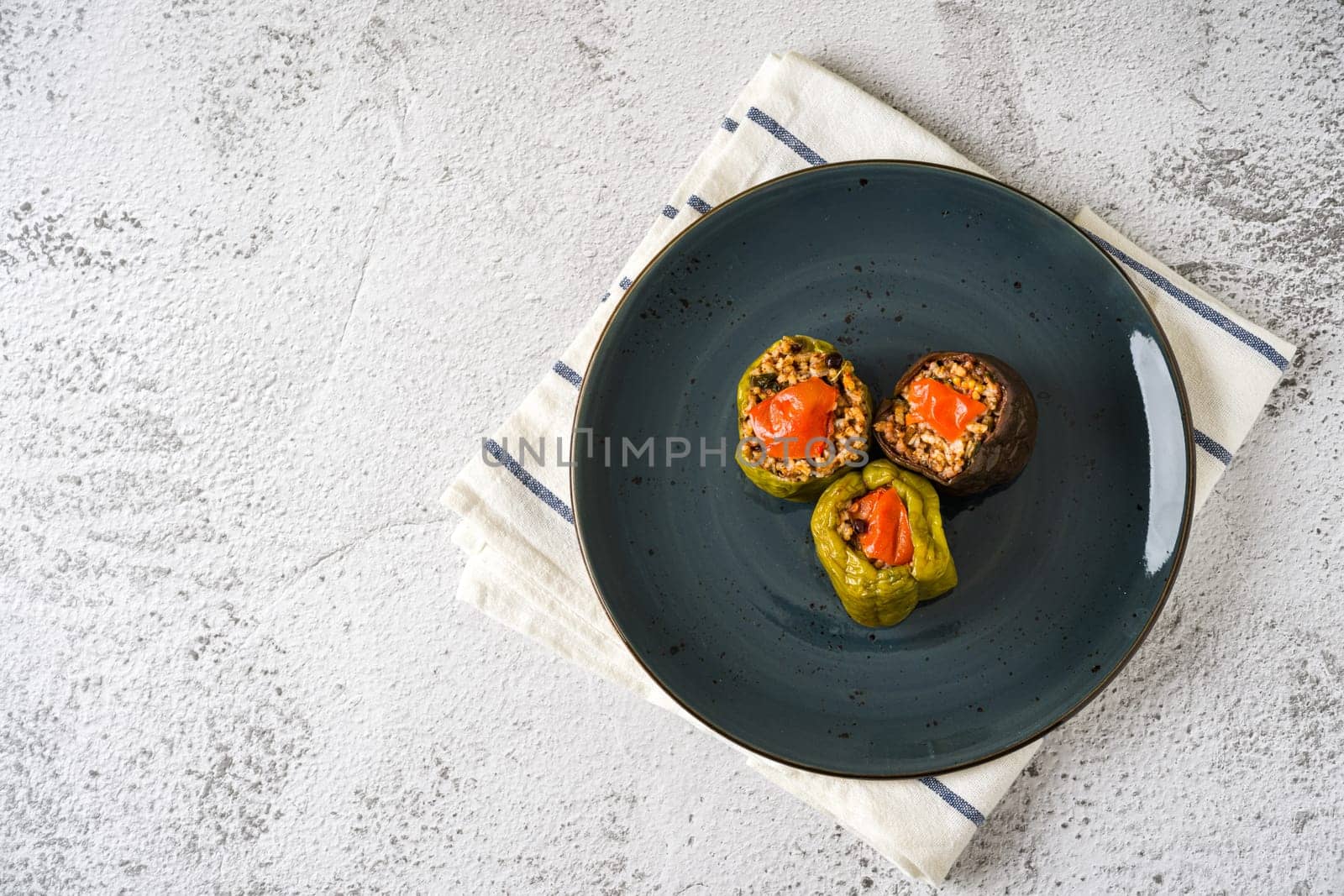 Stuffed green bell pepper and eggplant with olive oil on stone table by Sonat