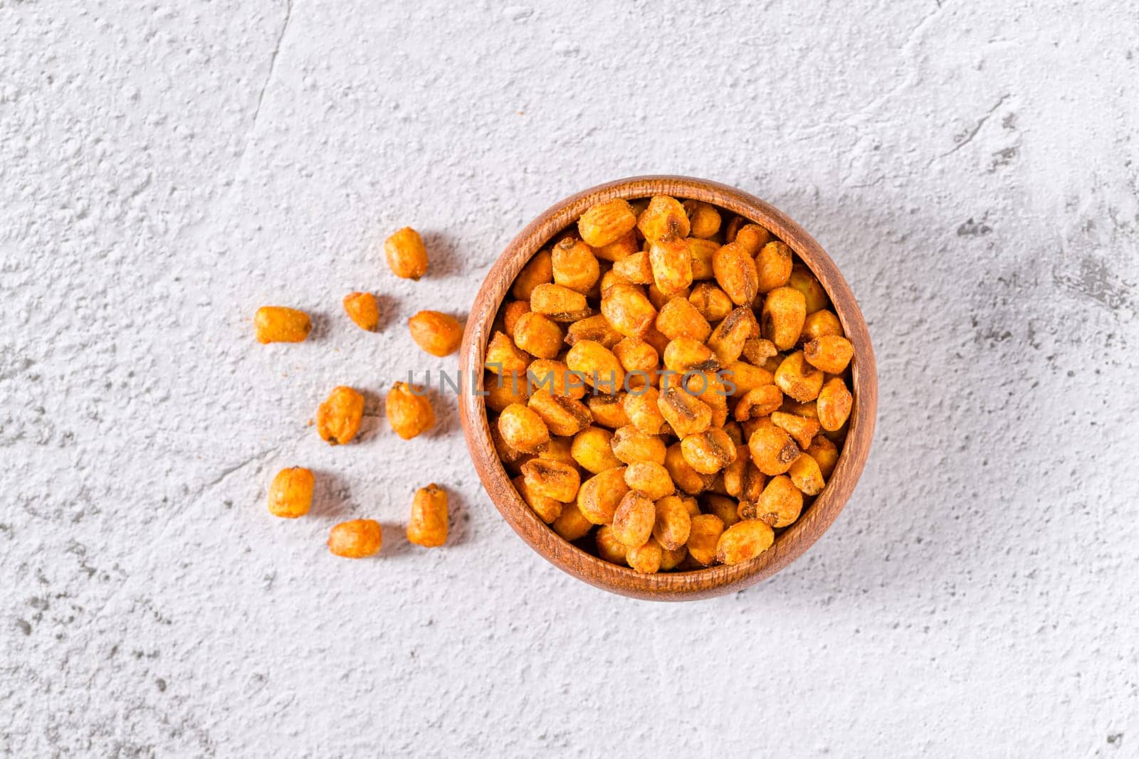 Roasted corn nuts with sauce in wooden bowl on white stone table