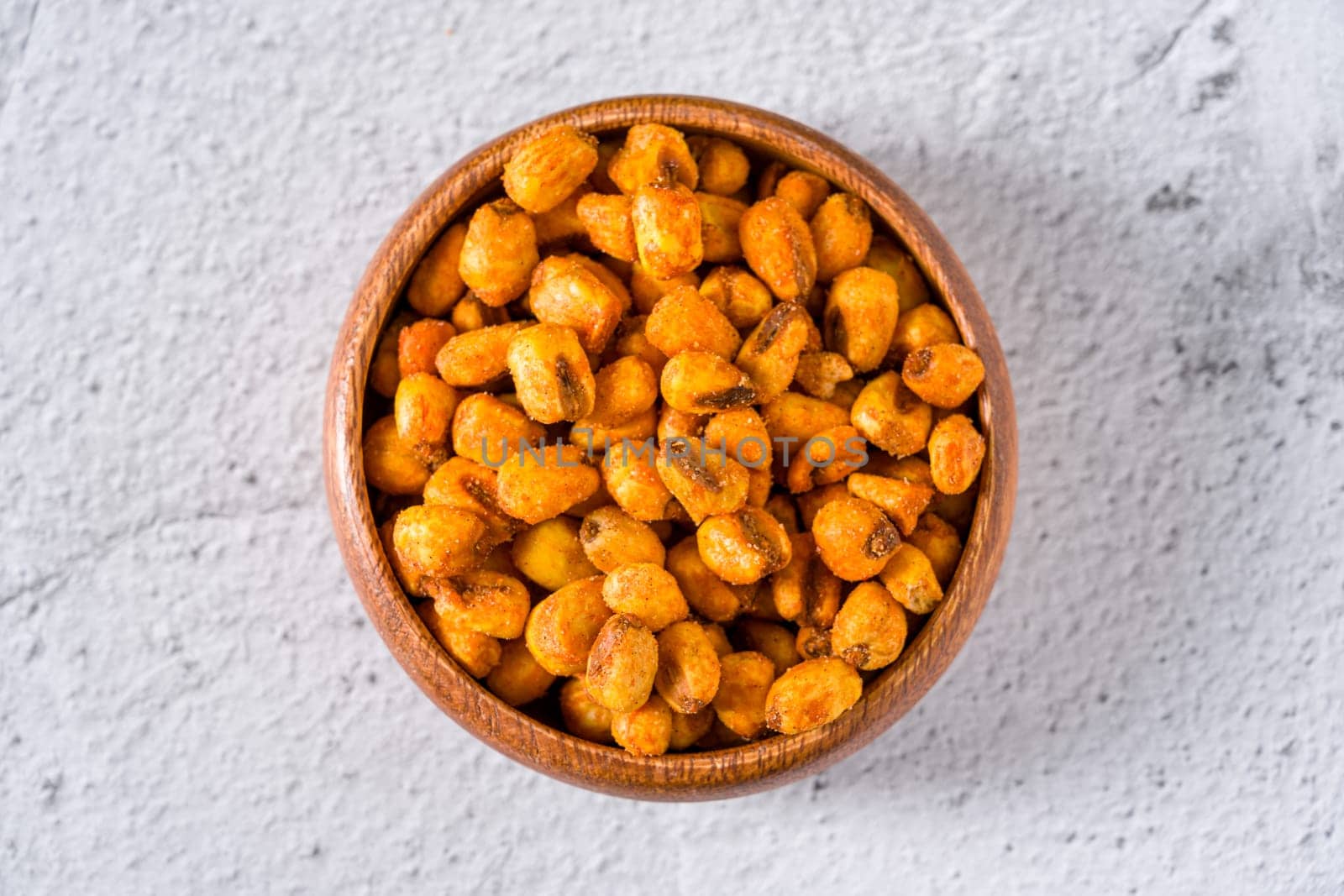 Roasted corn nuts with sauce in wooden bowl on white stone table