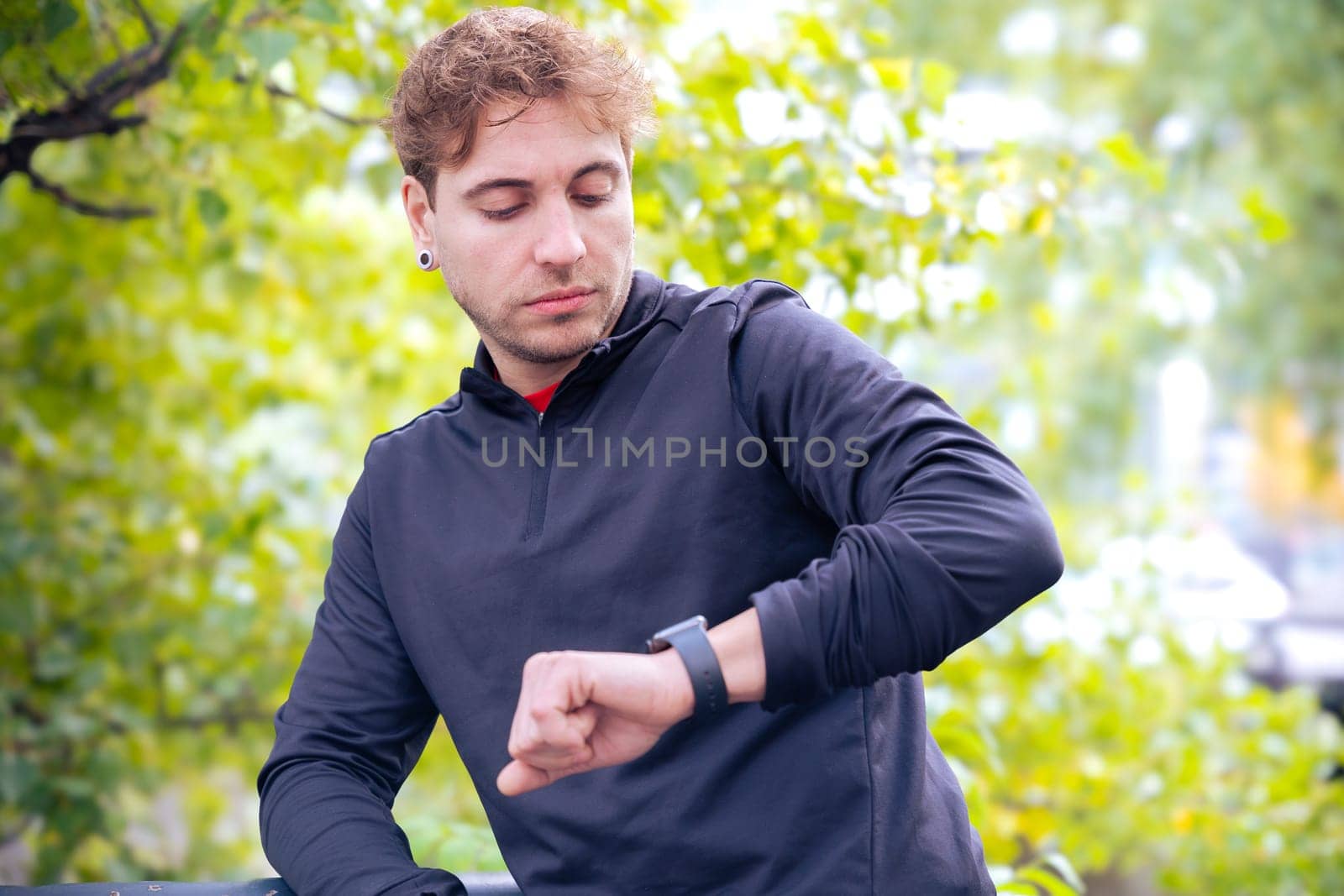 Sportsman looking at smartwatch with blank screen outdoors. by mariaphoto3