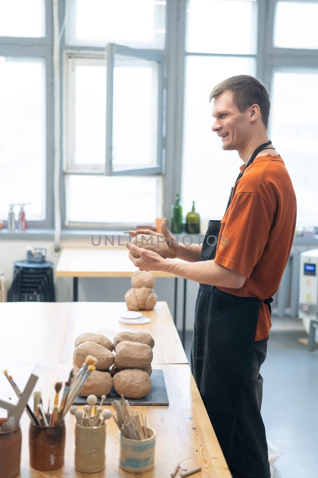 Potter kneads clay before using it in the workshop. Vertical photo. by mrwed54