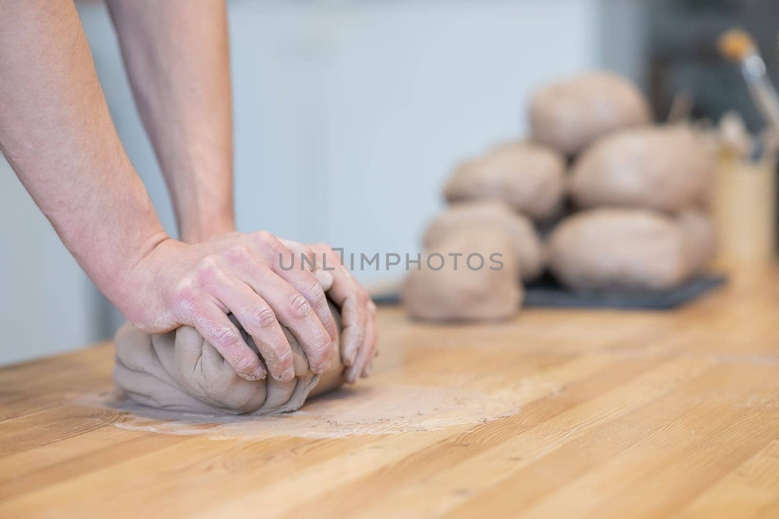 A potter kneads clay before using it in the workshop. Close-up of a man's hands