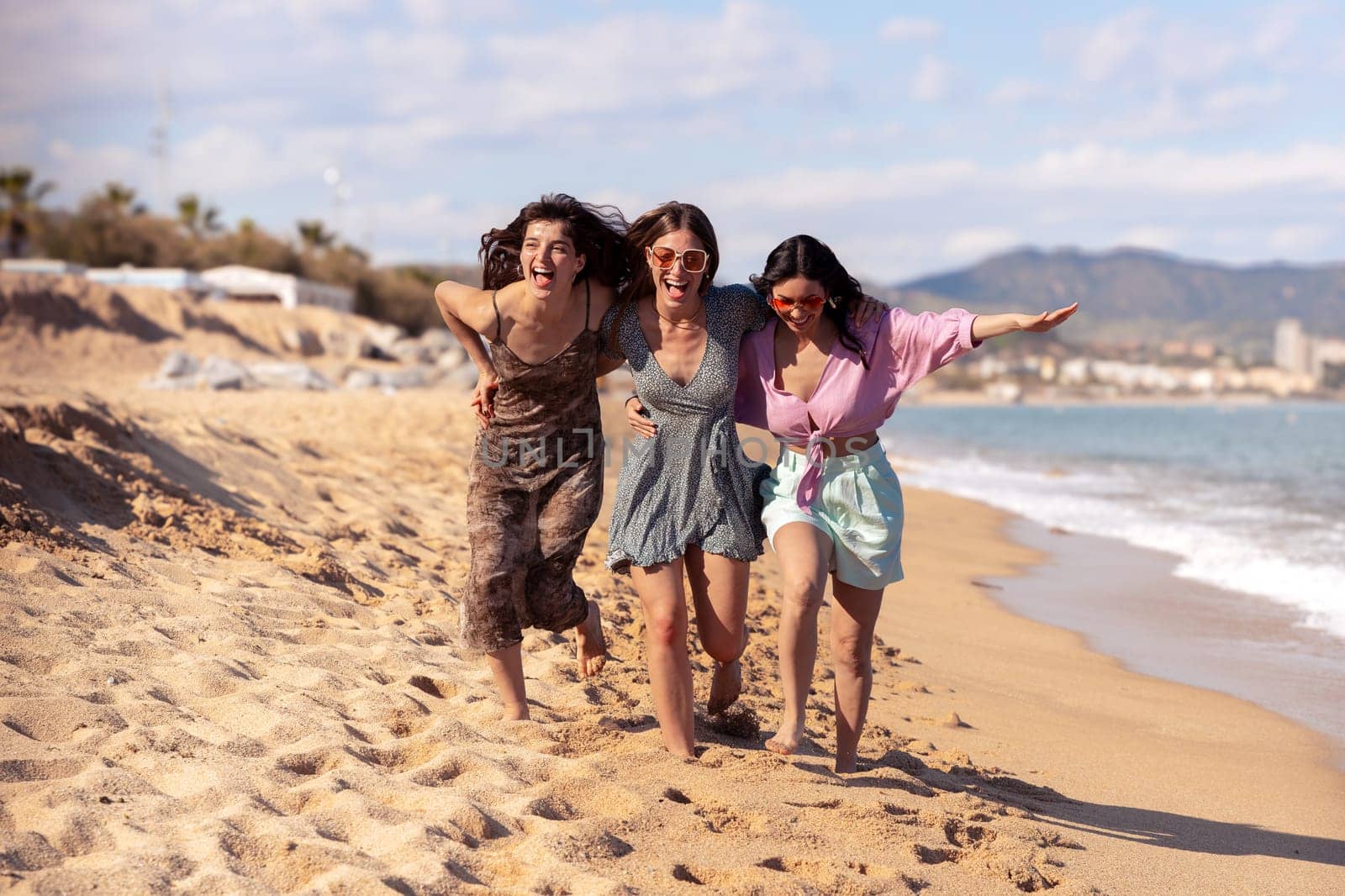 Portrait of three female friends walking on the beach having fun. by molesjuny