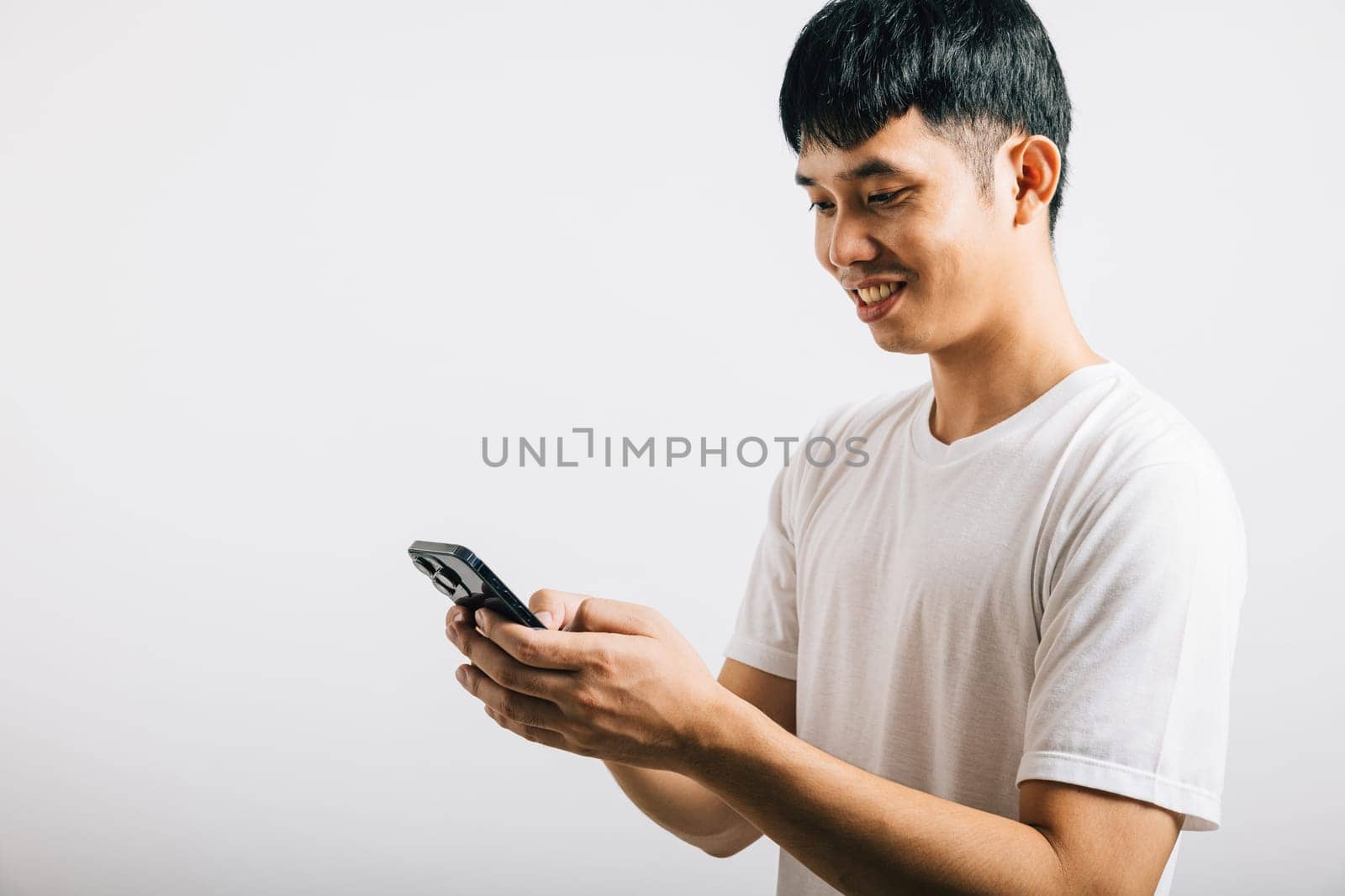 Portrait Asian smiling young man using mobile phone cellphone for social media studio isolated white background, Happy lifestyle men typing message on smartphone by Sorapop