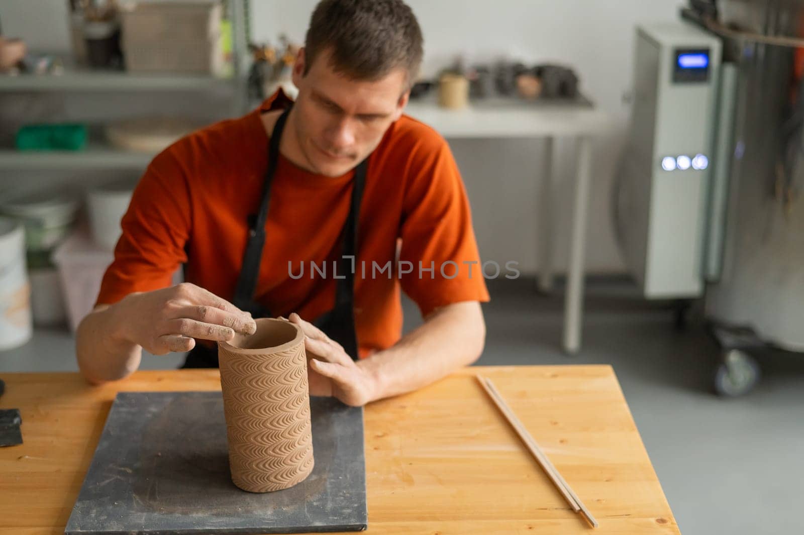 Potter sculpts a patterned cylinder from clay. by mrwed54