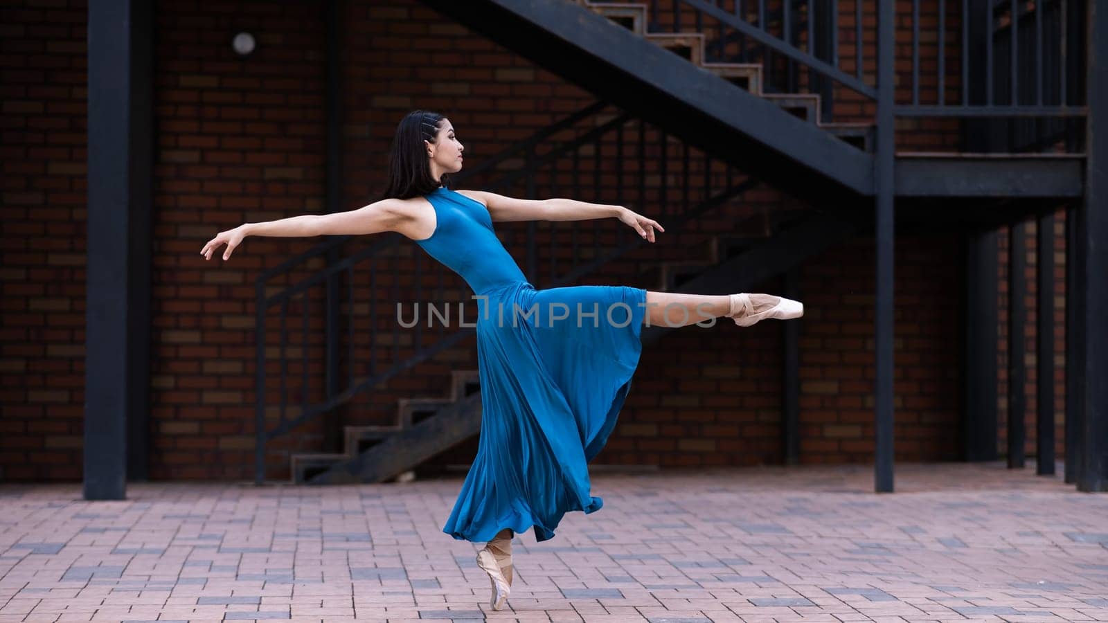 Beautiful Asian ballerina dancing outdoors. Urban landscape