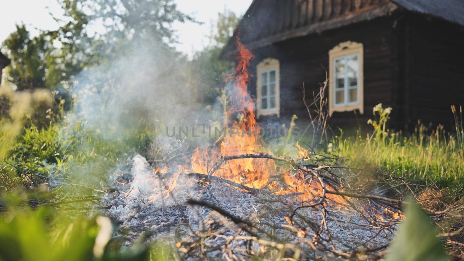 Burning branches outside the village house in eastern europe. by DovidPro