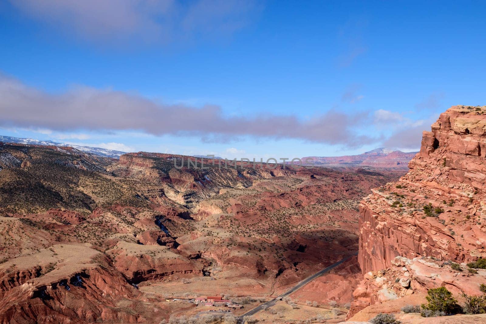 Stunning aerial view of Capitol Reef National Park in Utah, showcasing expansive red rock formations, rugged terrain, and a bright blue sky - Fruita District, USA