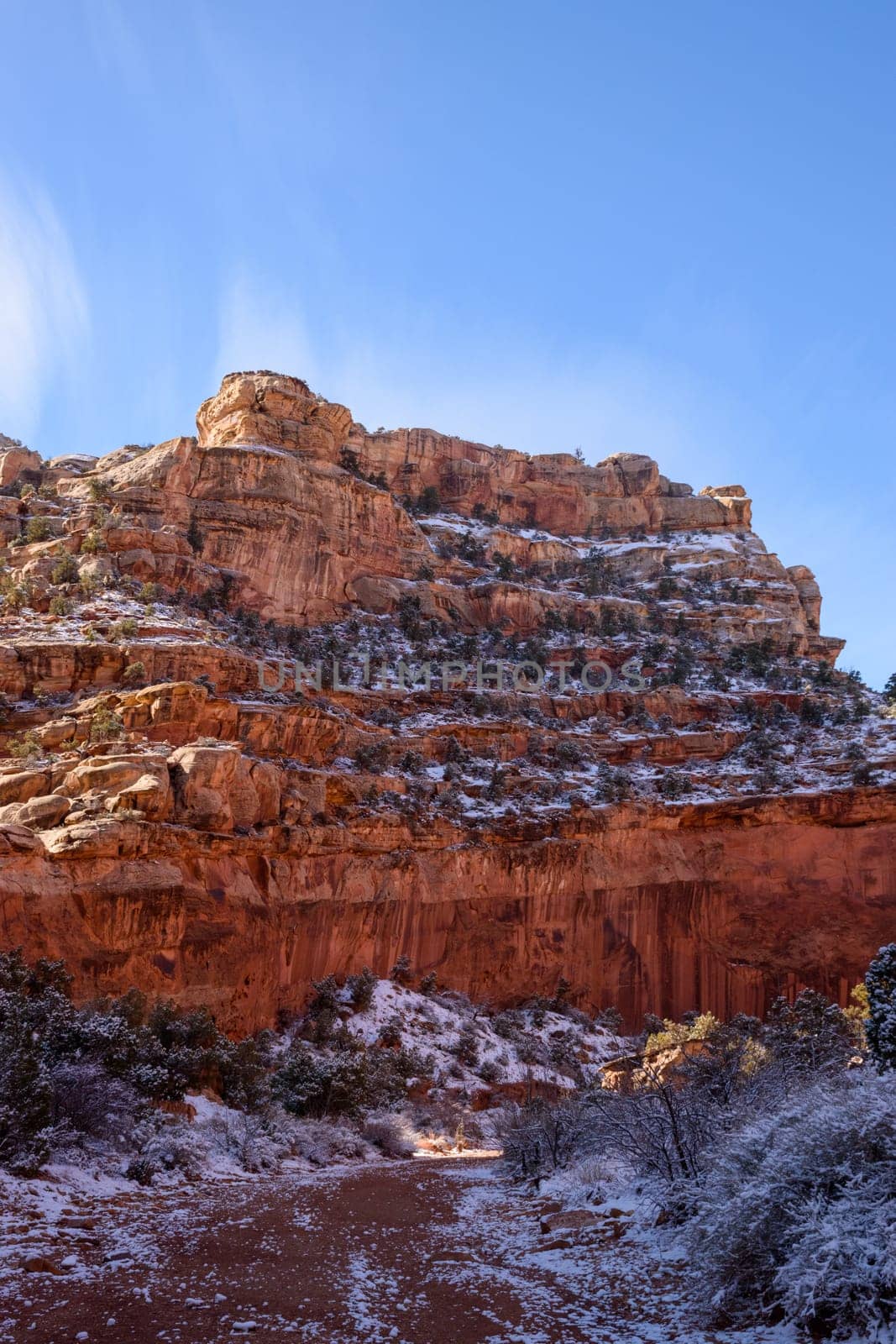 Beautiful winter landscape of the Grand Wash in Capitol Reef, Utah. Snow-dusted red rock canyon walls under a clear blue sky, offering a stunning natural scenery and peaceful atmosphere - USA