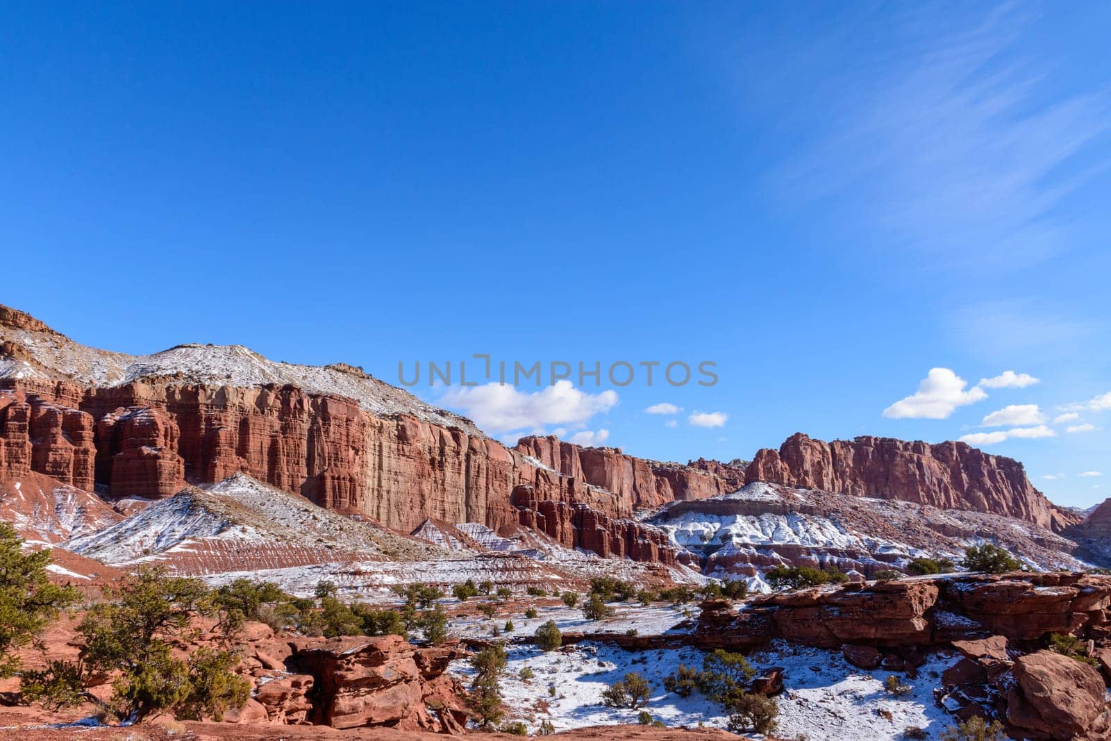 Stunning snow-covered red rock formations under a clear blue sky in Capitol Reef National Park, Utah. Winter scenery showcases the park's geological features and breathtaking natural beauty - USA