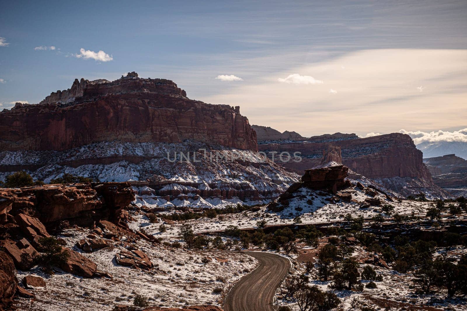 Stunning view of Capitol Reef National Park in Utah during winter. The rugged terrain, snow-dusted mountains, and winding road create a breathtaking landscape under a clear sky - USA