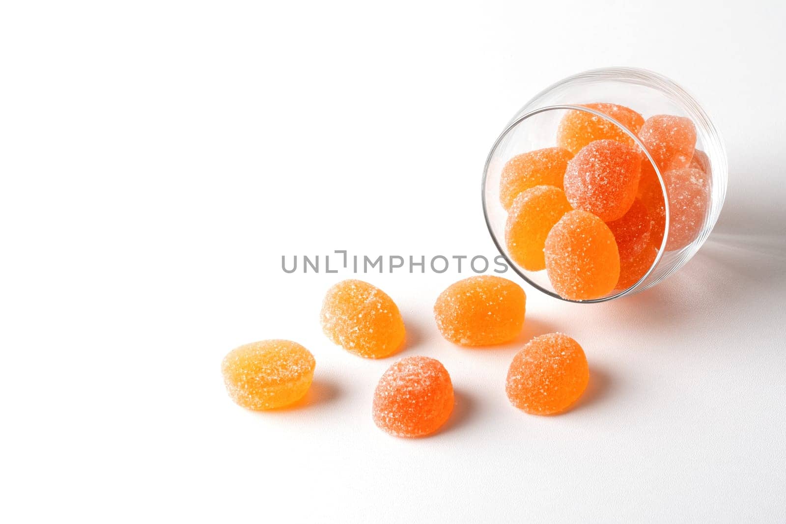 Pieces of apricot marmalade poured from a glass bowl on a white table..