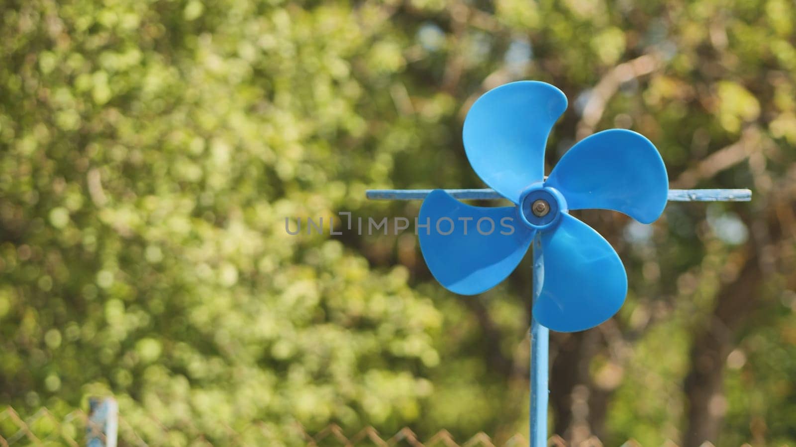 A blue vane weathervane spins in the wind in the summer. by DovidPro