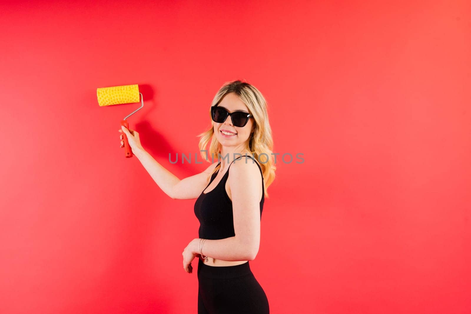 Young minded employee laborer handyman woman choosing a roller brush paint