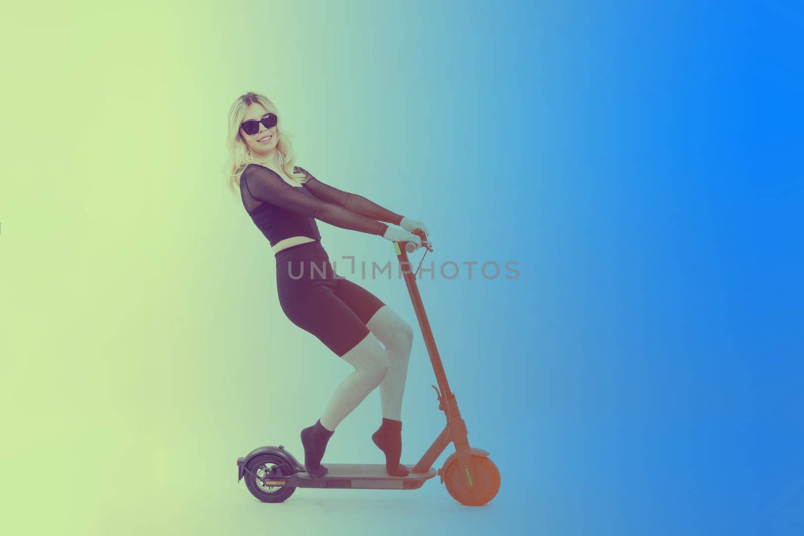 A blonde woman on red background sitting on electro scooter and resting, copy space by Zelenin