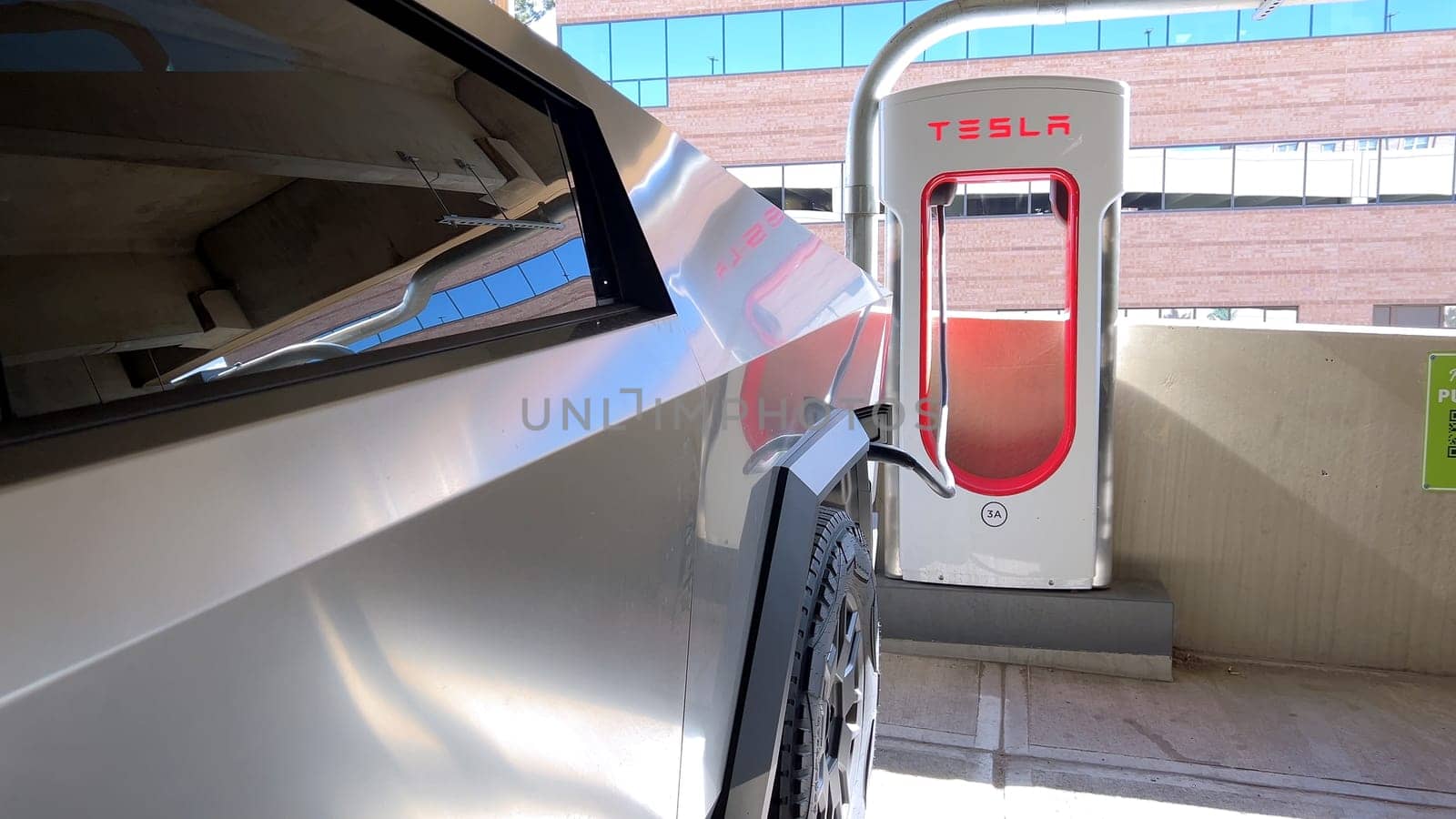 Pueblo, Colorado, USA-June 10, 2024-Slow motion-A Tesla Cybertruck is parked and charging at a Tesla Supercharger station in an underground parking garage. The futuristic design of the Cybertruck stands out against the industrial background.