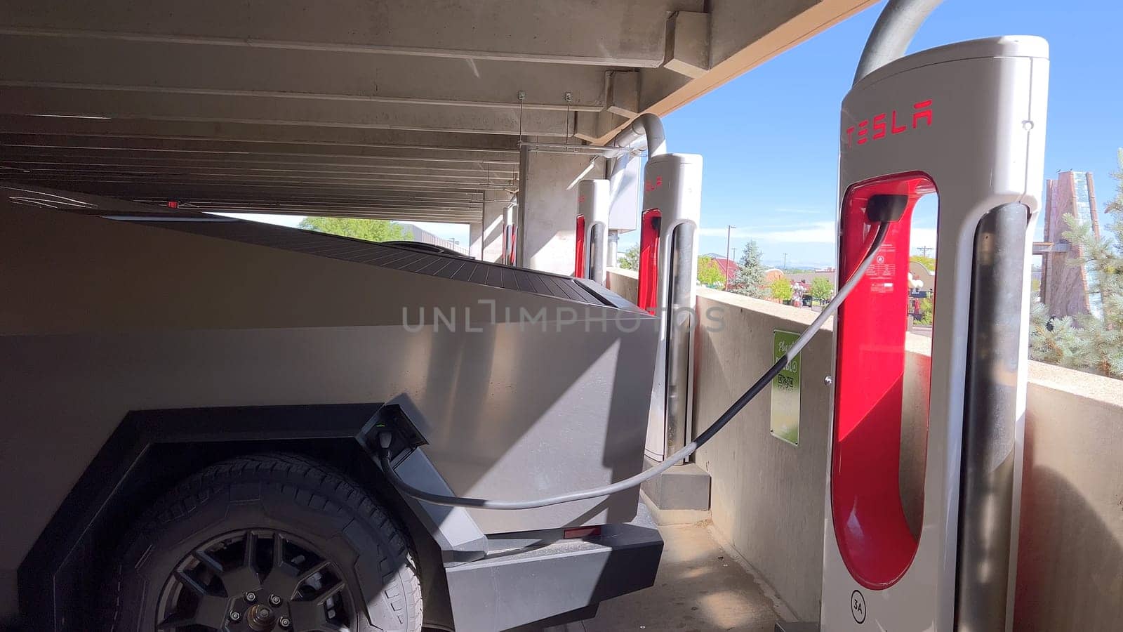 Pueblo, Colorado, USA-June 10, 2024-Slow motion-A Tesla Cybertruck is parked and charging at a Tesla Supercharger station in an underground parking garage. The futuristic design of the Cybertruck stands out against the industrial background.