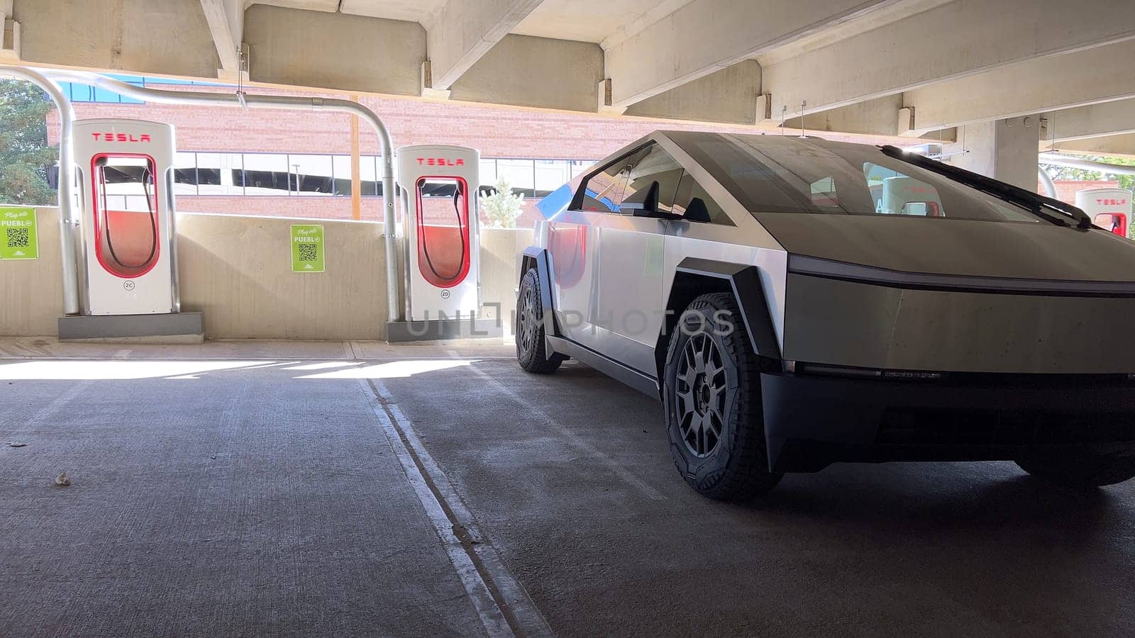 Pueblo, Colorado, USA-June 10, 2024-Slow motion-A Tesla Cybertruck is parked and charging at a Tesla Supercharger station in an underground parking garage. The futuristic design of the Cybertruck stands out against the industrial background.