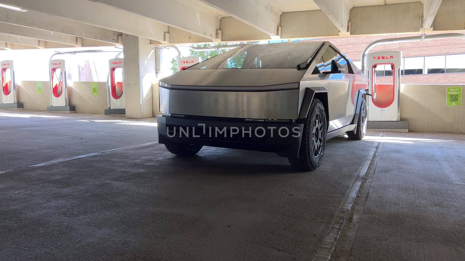 Pueblo, Colorado, USA-June 10, 2024-Slow motion-A Tesla Cybertruck is parked and charging at a Tesla Supercharger station in an underground parking garage. The futuristic design of the Cybertruck stands out against the industrial background.