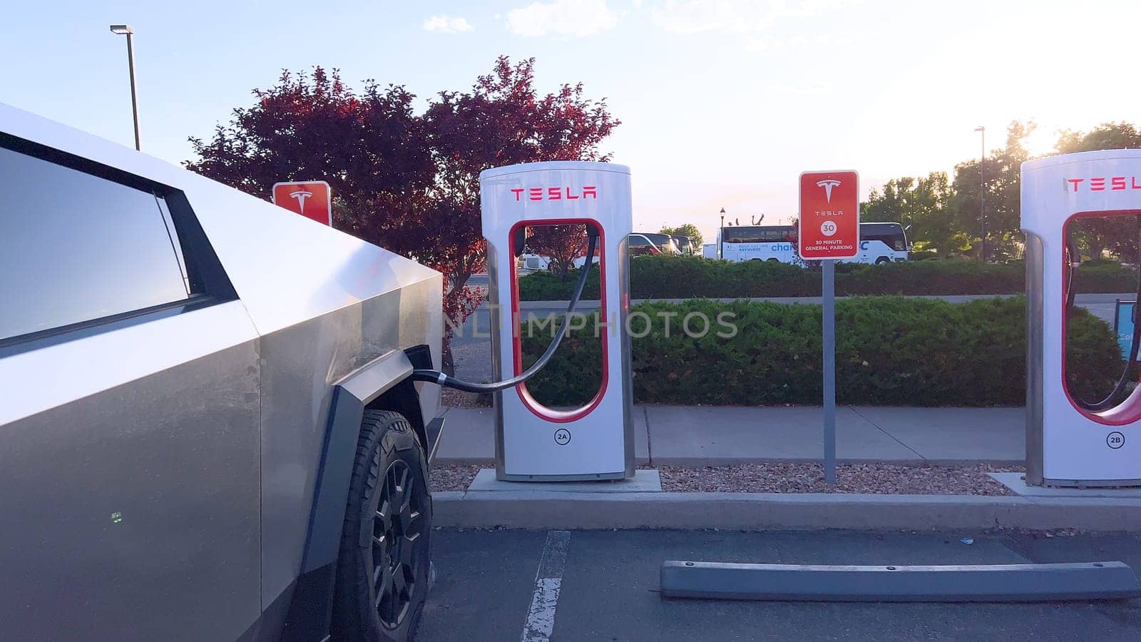 Santa Fe, New Mexico, USA-June 10, 2024-Slow motion-A Tesla Cybertruck is connected to a Tesla Supercharger at an outdoor charging station. The sleek, angular design of the Cybertruck is highlighted by the sunlight, emphasizing its modern and futuristic appearance.