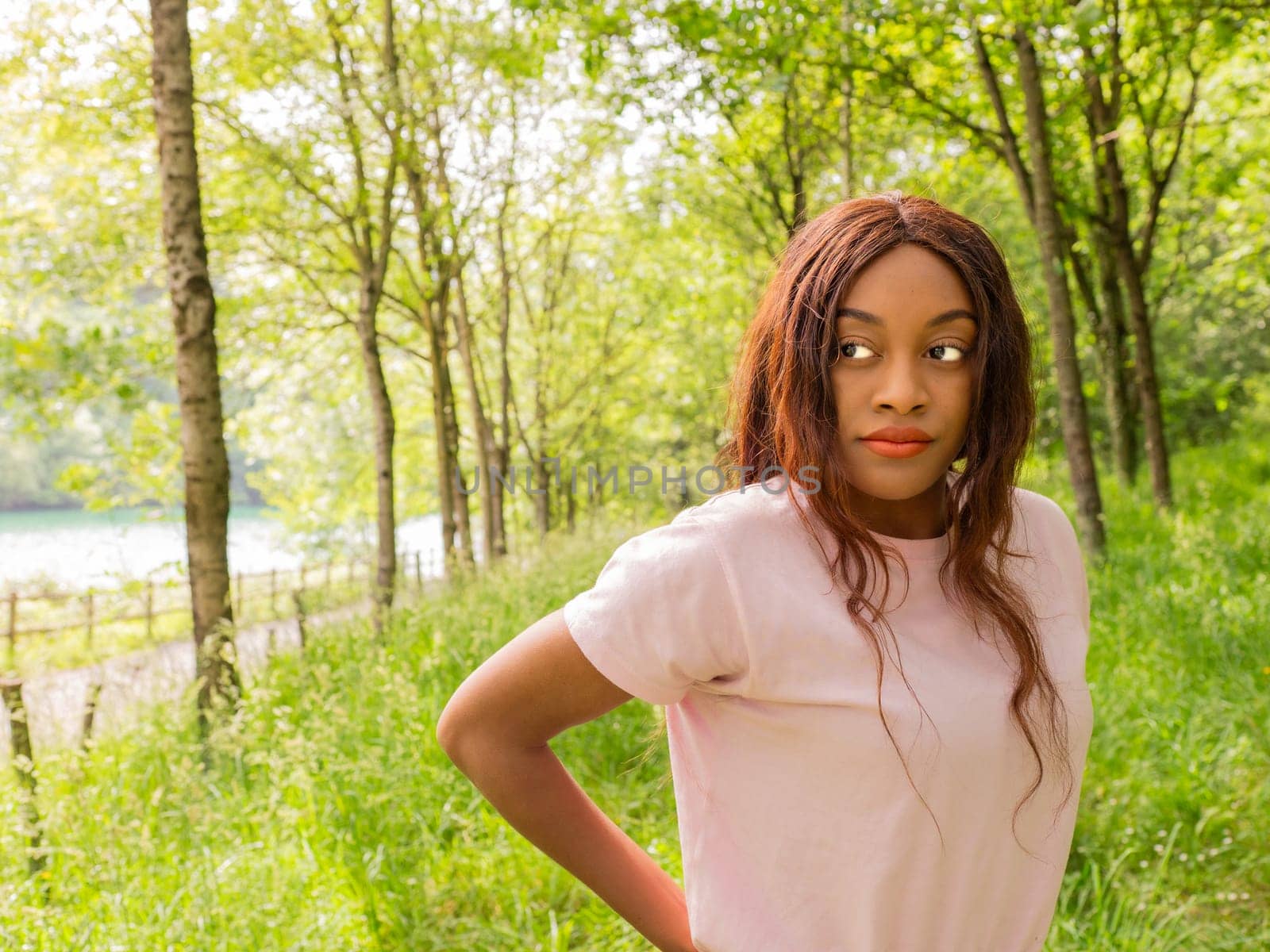 A woman confidently stands in a field, with her hands resting on her hips.