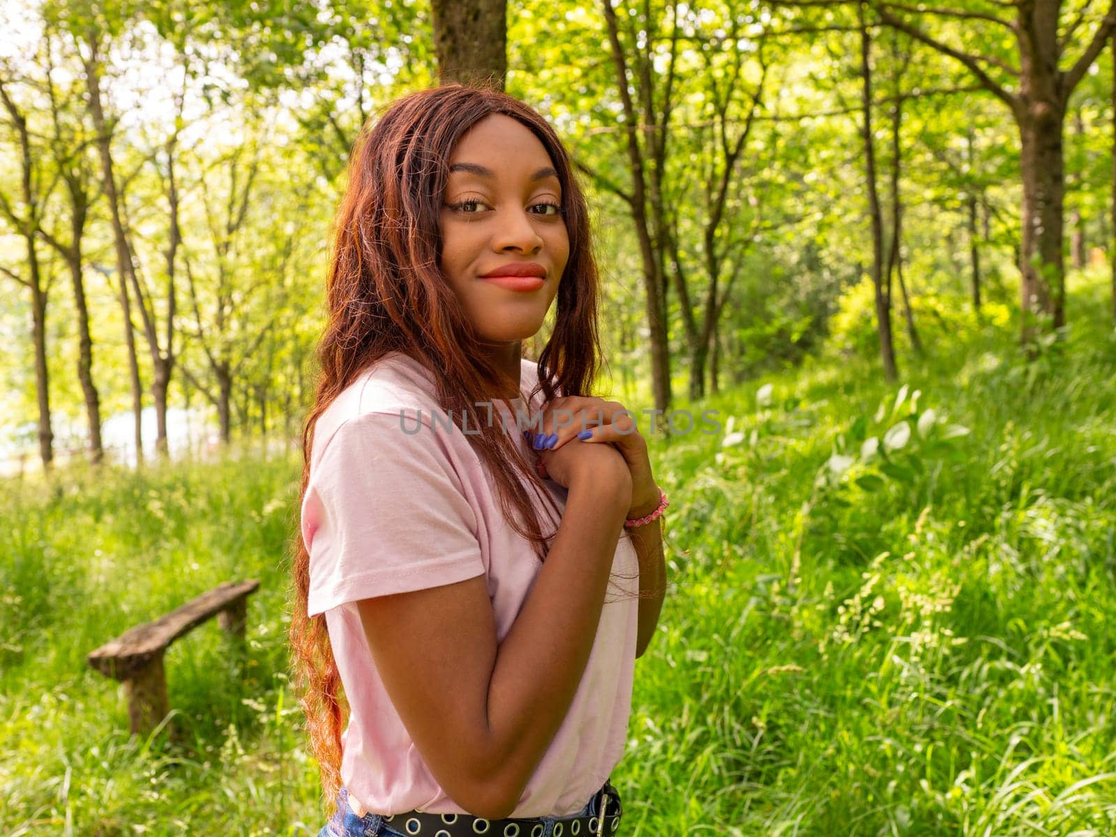 A woman standing in a grassy area with trees in the background.