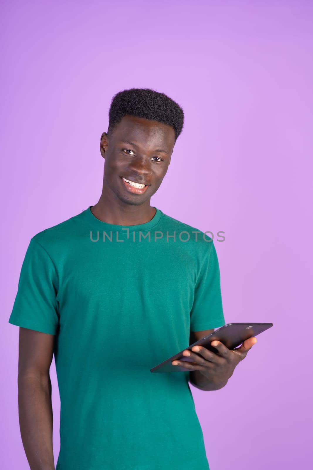 A man wearing a green shirt is holding a tablet device in his hands.