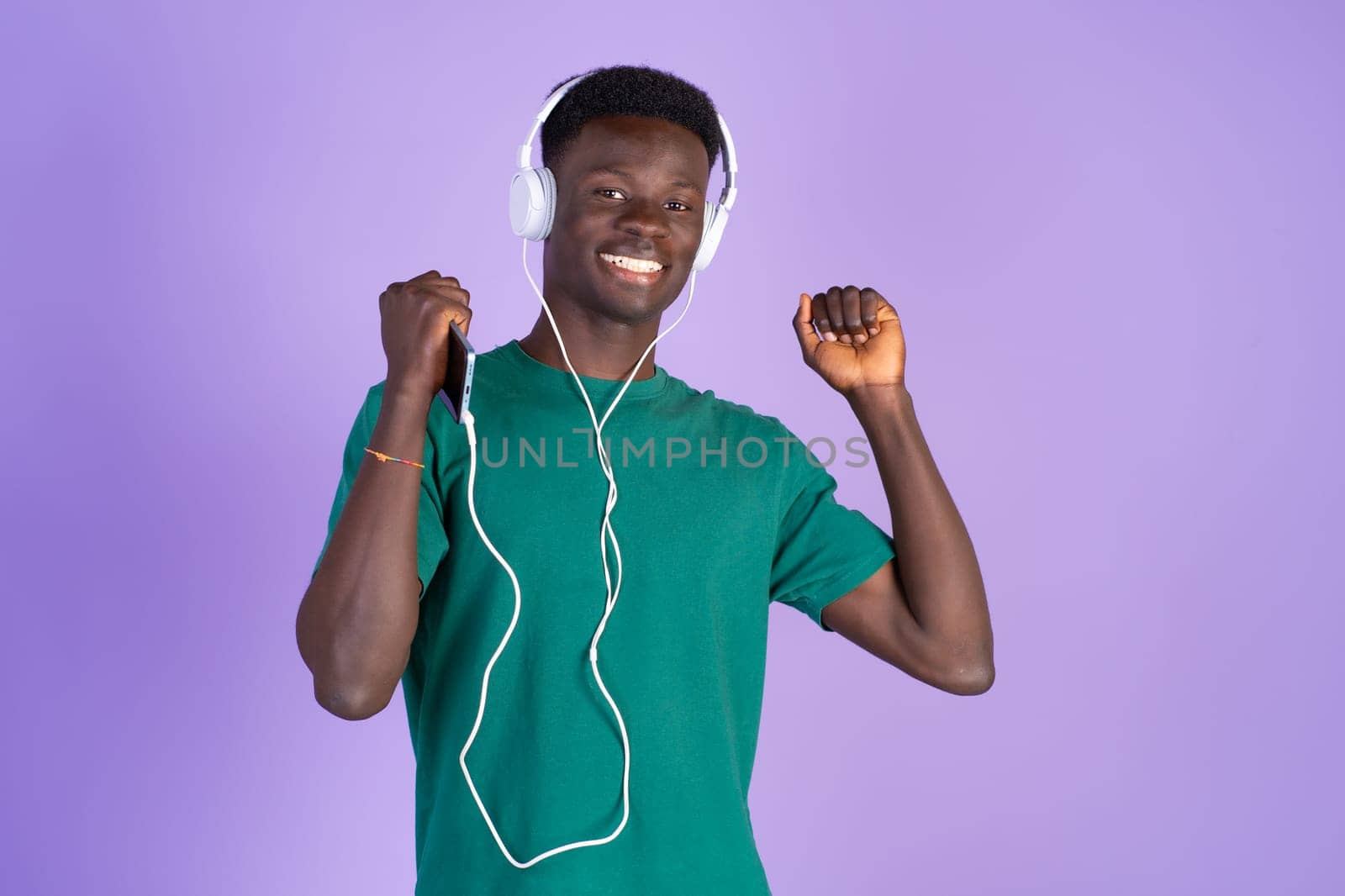 A man in a green shirt is wearing headphones while standing.