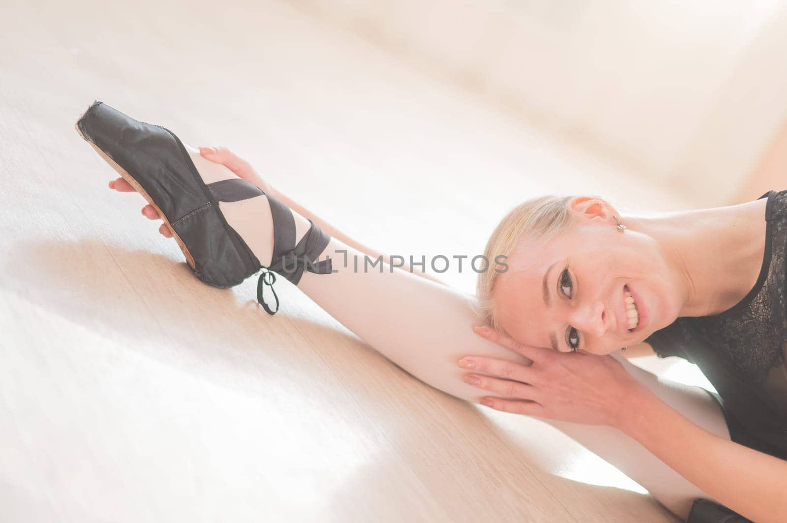 A young woman lies bent over on her feet in a ballet class. Ballerina stretches on the floor. by mrwed54