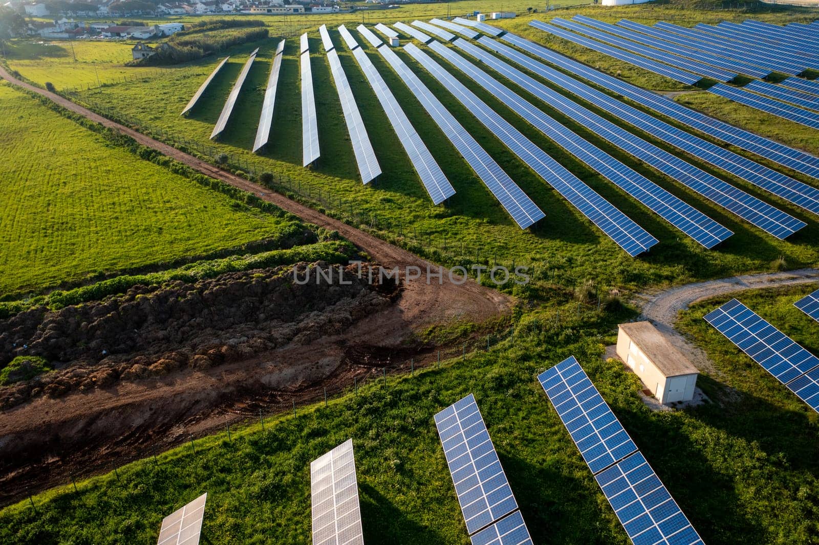 Agricultural field with row of solar panels, blending into the natural landscape of grassy plains from an aerial view