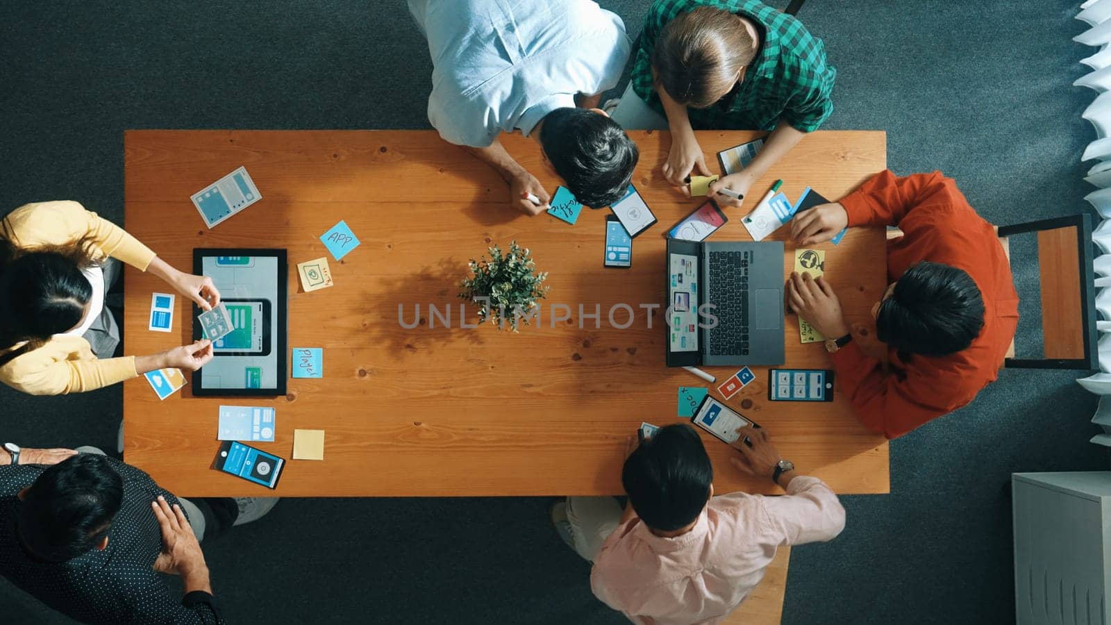 Programmer team brainstorm and plan Ux Ui design for mobile phone while present idea by using laptop at meeting. Software developer look at wireframe prototype while write at sticky note.Convocation.