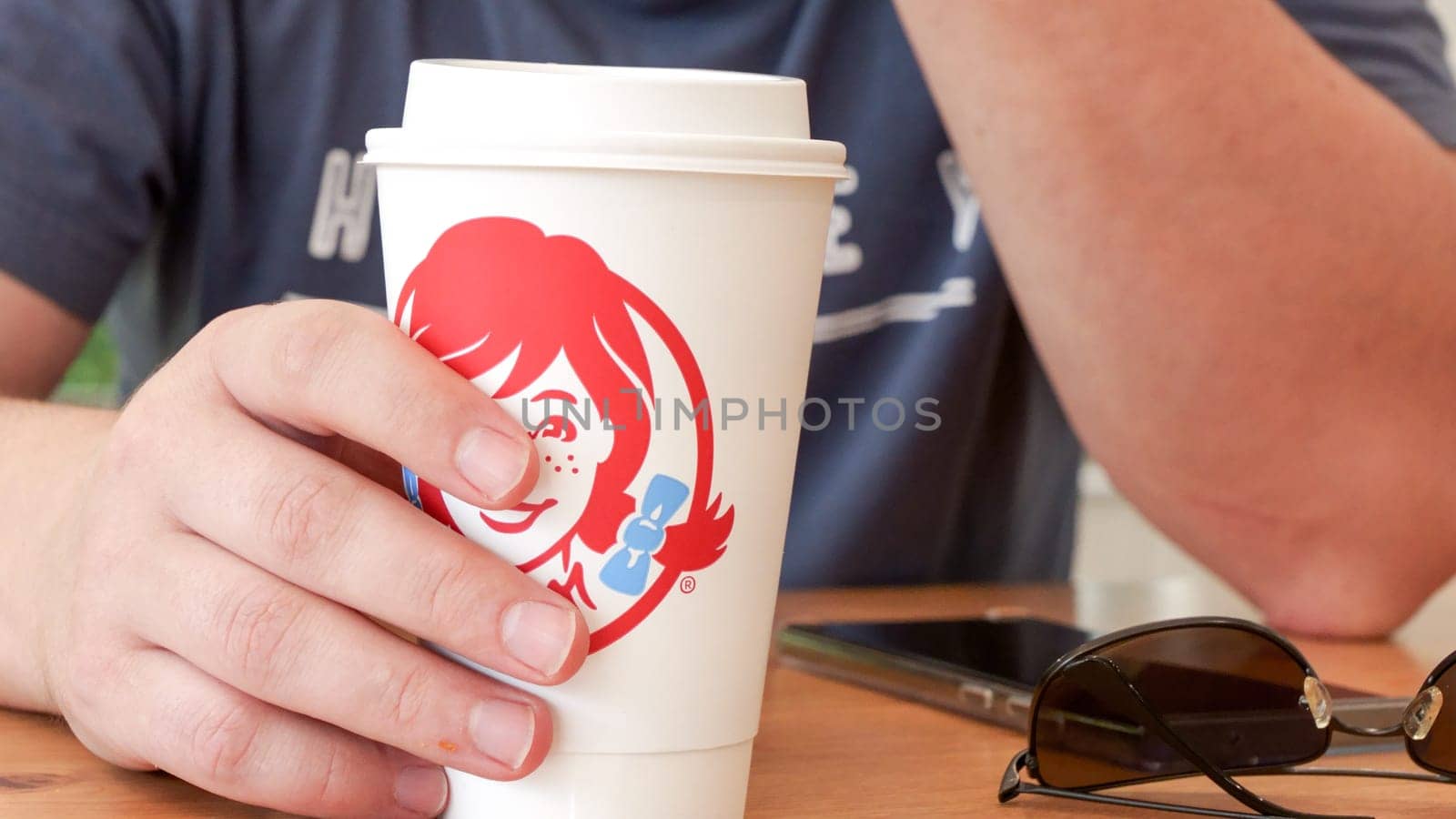 Wendys Fast food Clear plastic cup with red soda on wooden table with brown paper bag in background New York NY USA 2023-07-30 by JuliaDorian