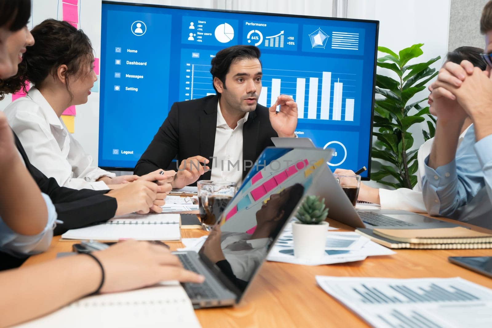 Diverse group of business analyst team analyzing financial data report. Finance data analysis chart and graph dashboard show on TV screen in meeting room for strategic marketing planning. Habiliment