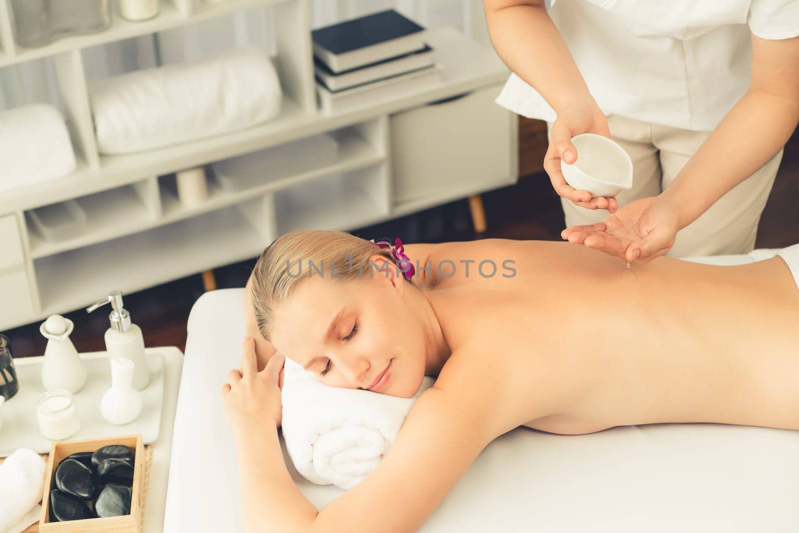 Masseur hands pouring aroma oil on woman back. Masseuse prepare oil massage procedure for customer at spa salon in luxury resort. Aroma oil body massage therapy concept. Quiescent