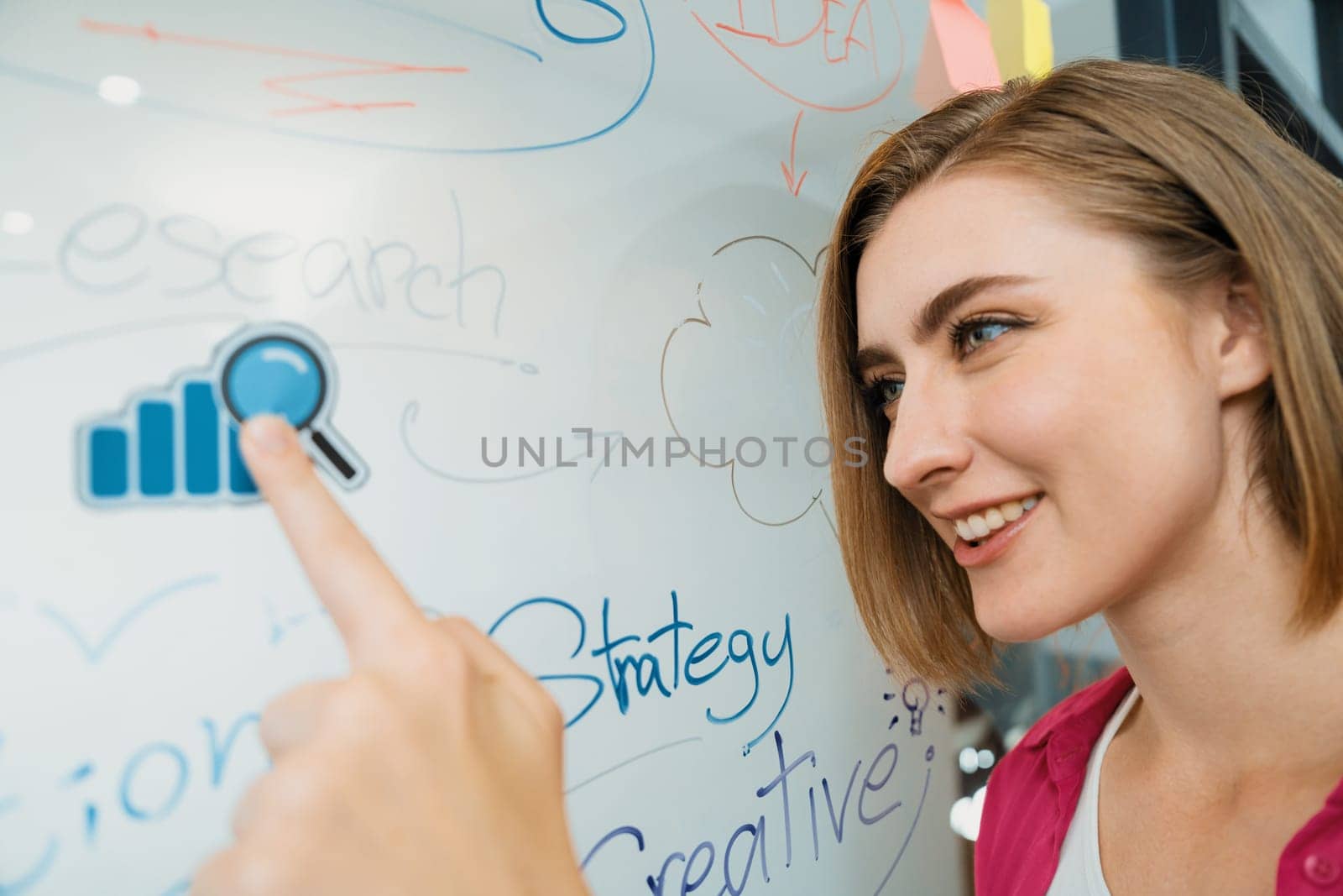 Young beautiful businesswoman putting sticker on glass board while finding a solution to solve financial problems by using mind map and colorful sticky note. Creative business concept. Immaculate.