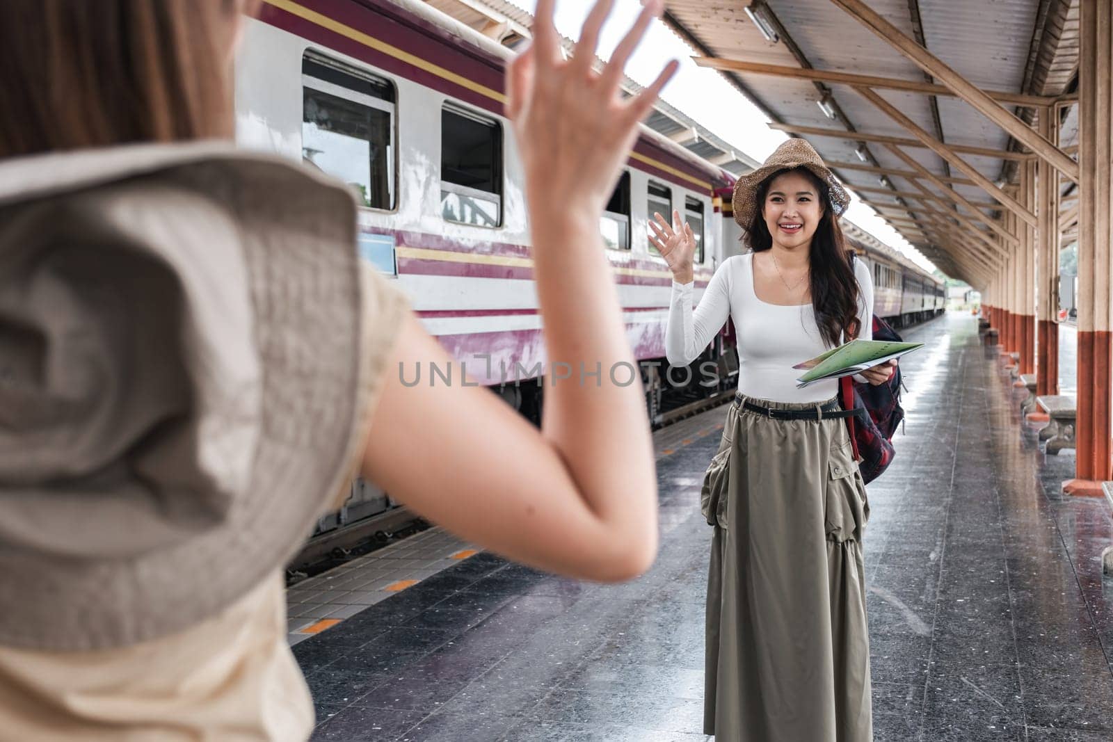 Asian woman waving at friend at train station, concept of reunion.