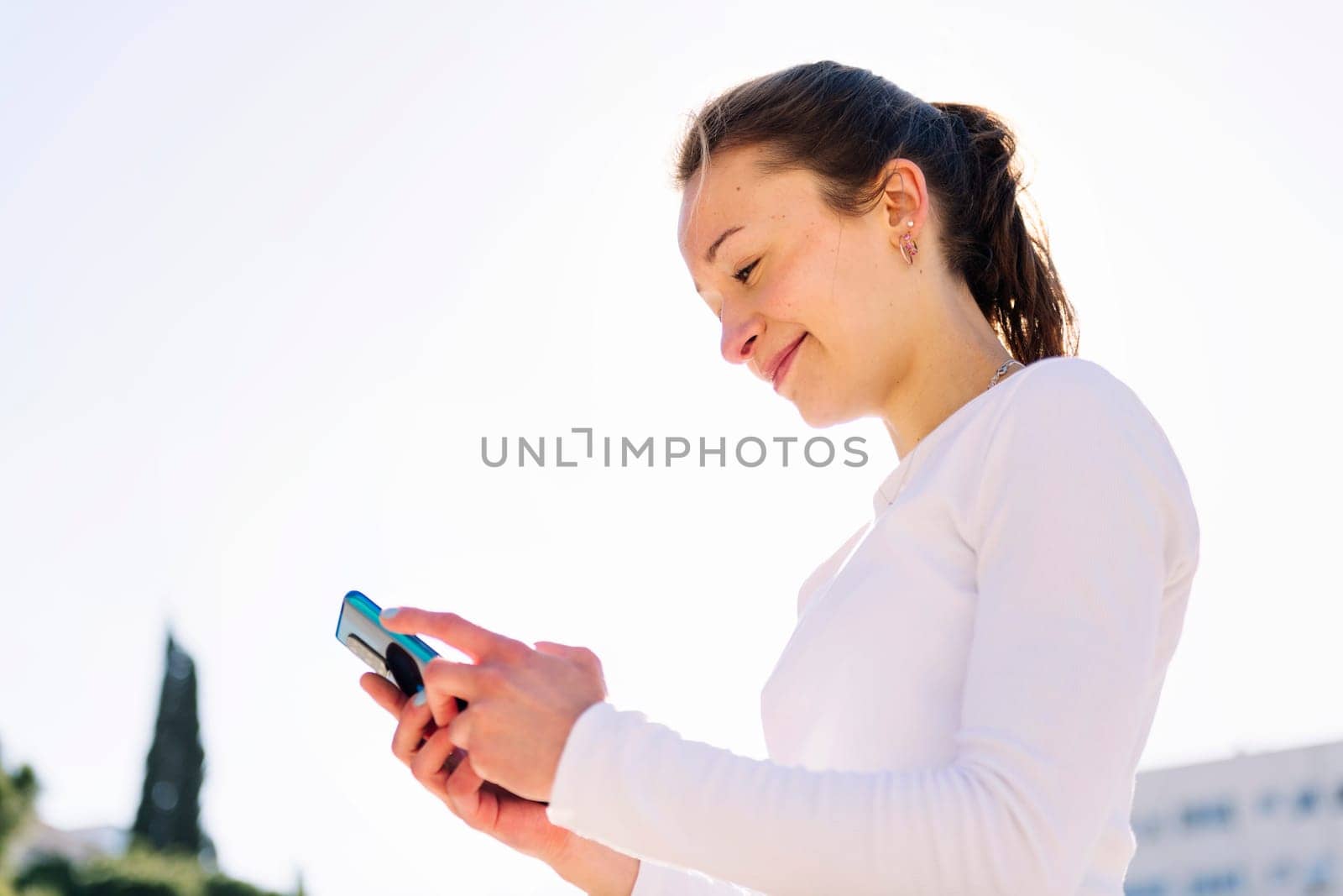 smiling young woman using mobile phone, concept of technology of communication and social media