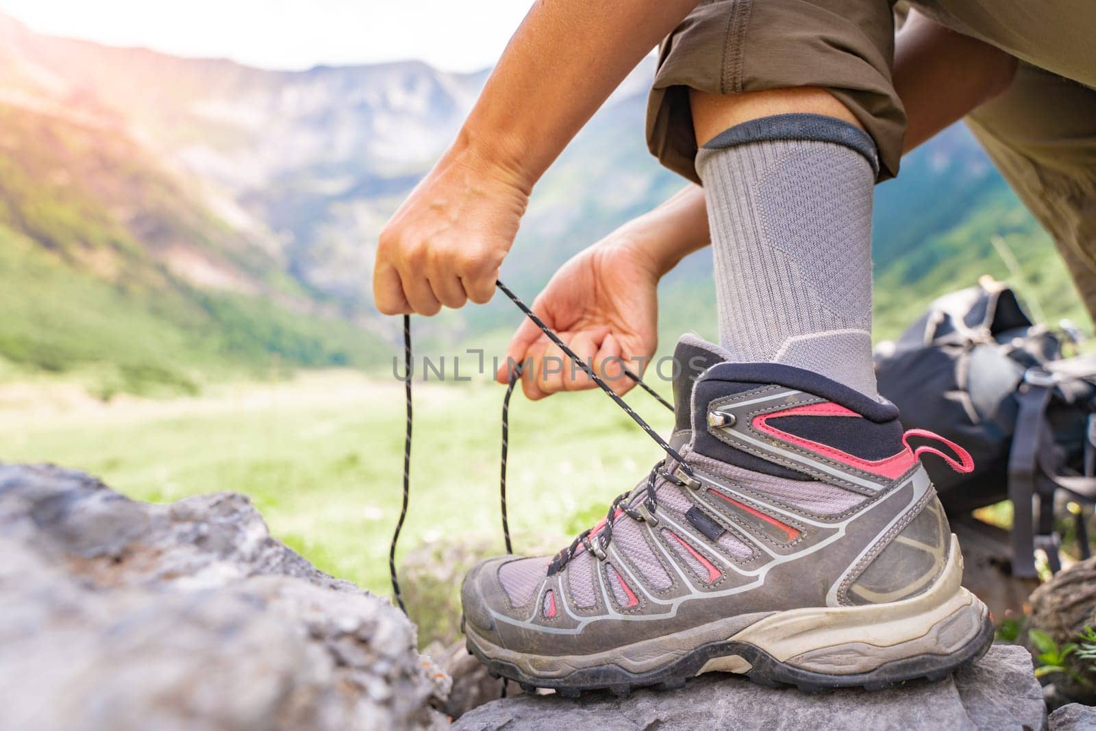 Woman tying hiking boot outdoors on trail in summer. High quality photo